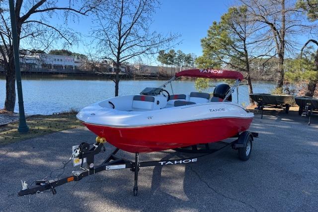 2026 Tahoe T16 boat on trailer by a lakeside, featuring a red and white design.