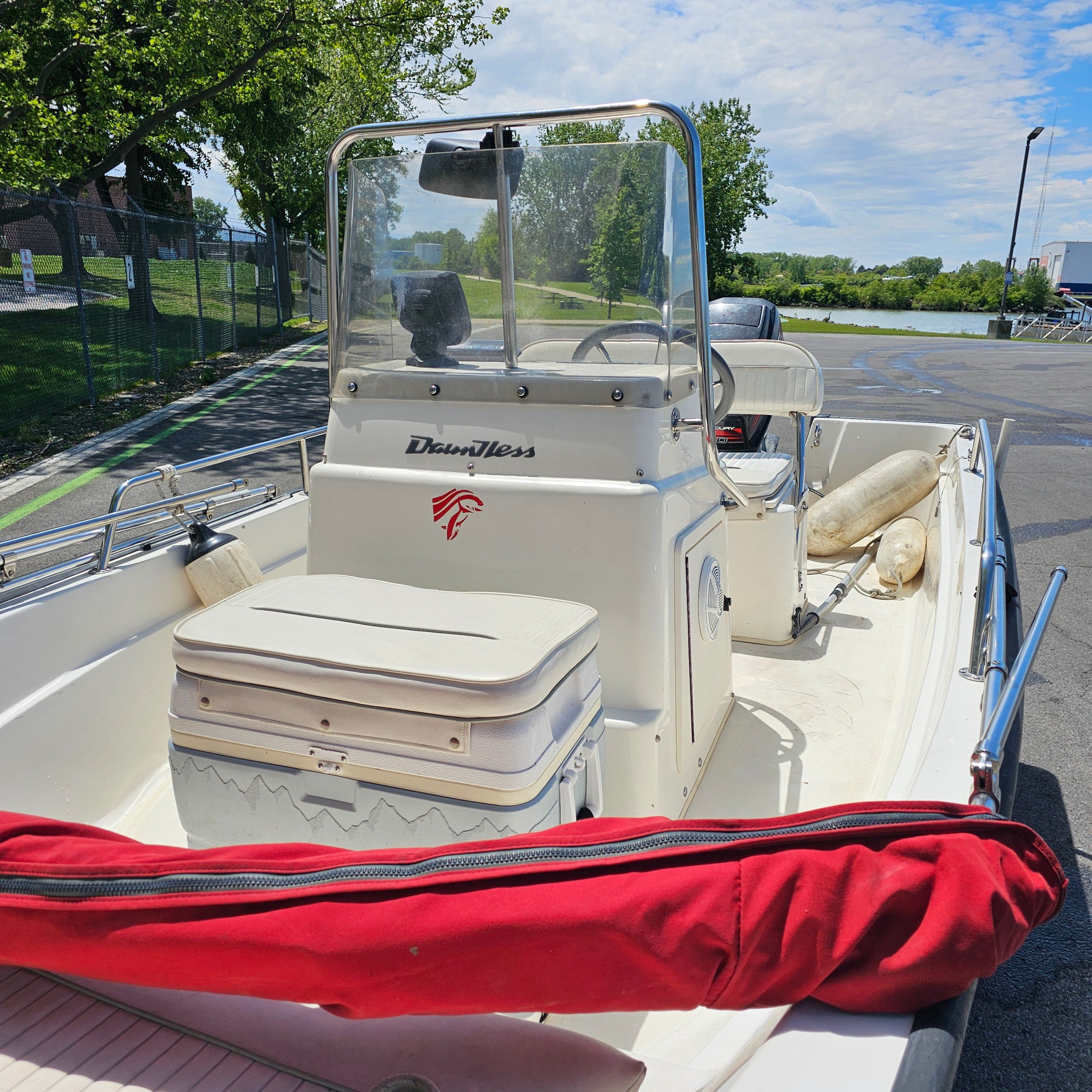 A Boston Whaler Dauntless 15 boat with a console and seating, parked on a lot.