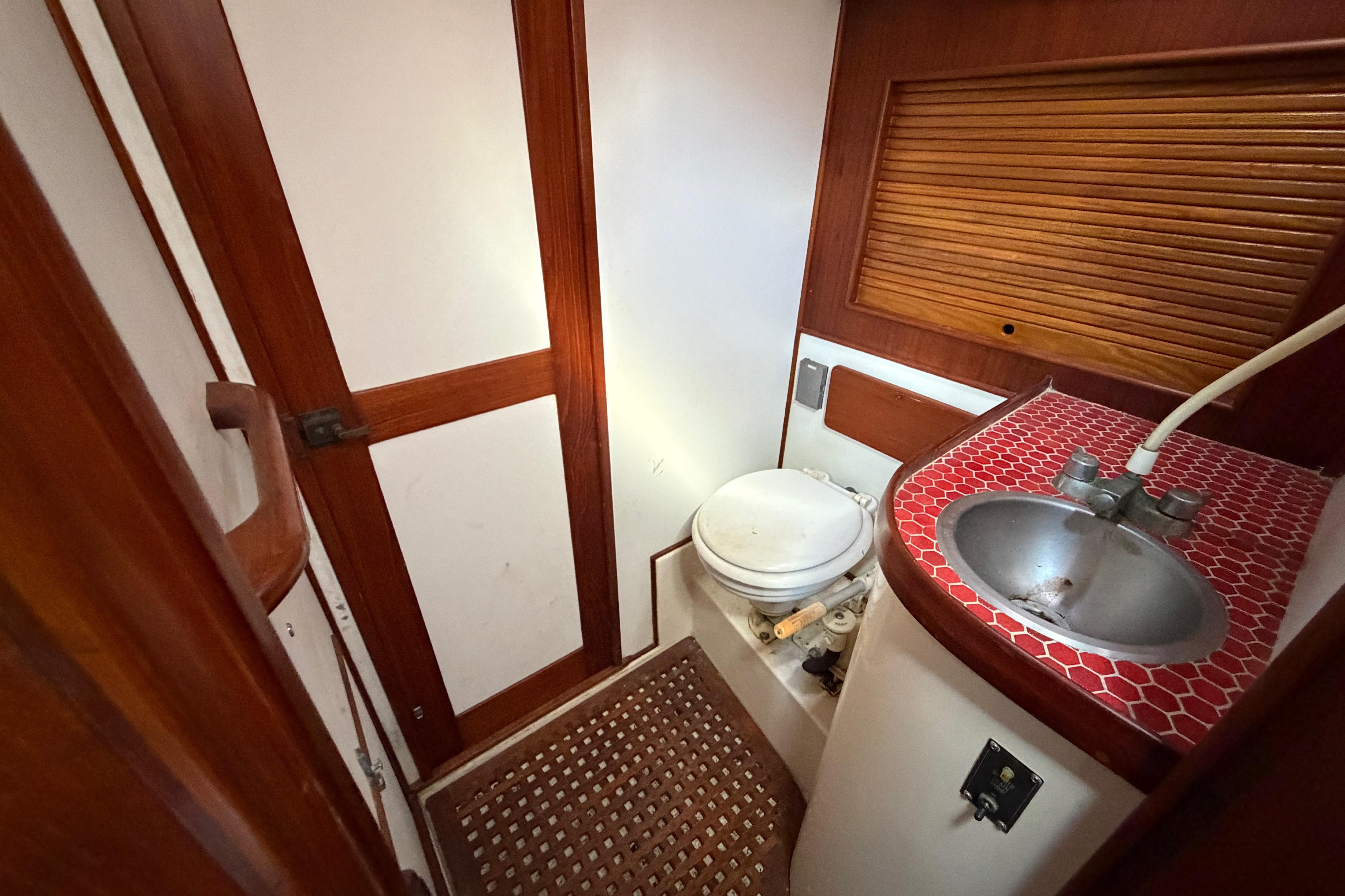 1983 Morgan Catilina boat bathroom with red-tiled sink and wooden accents.