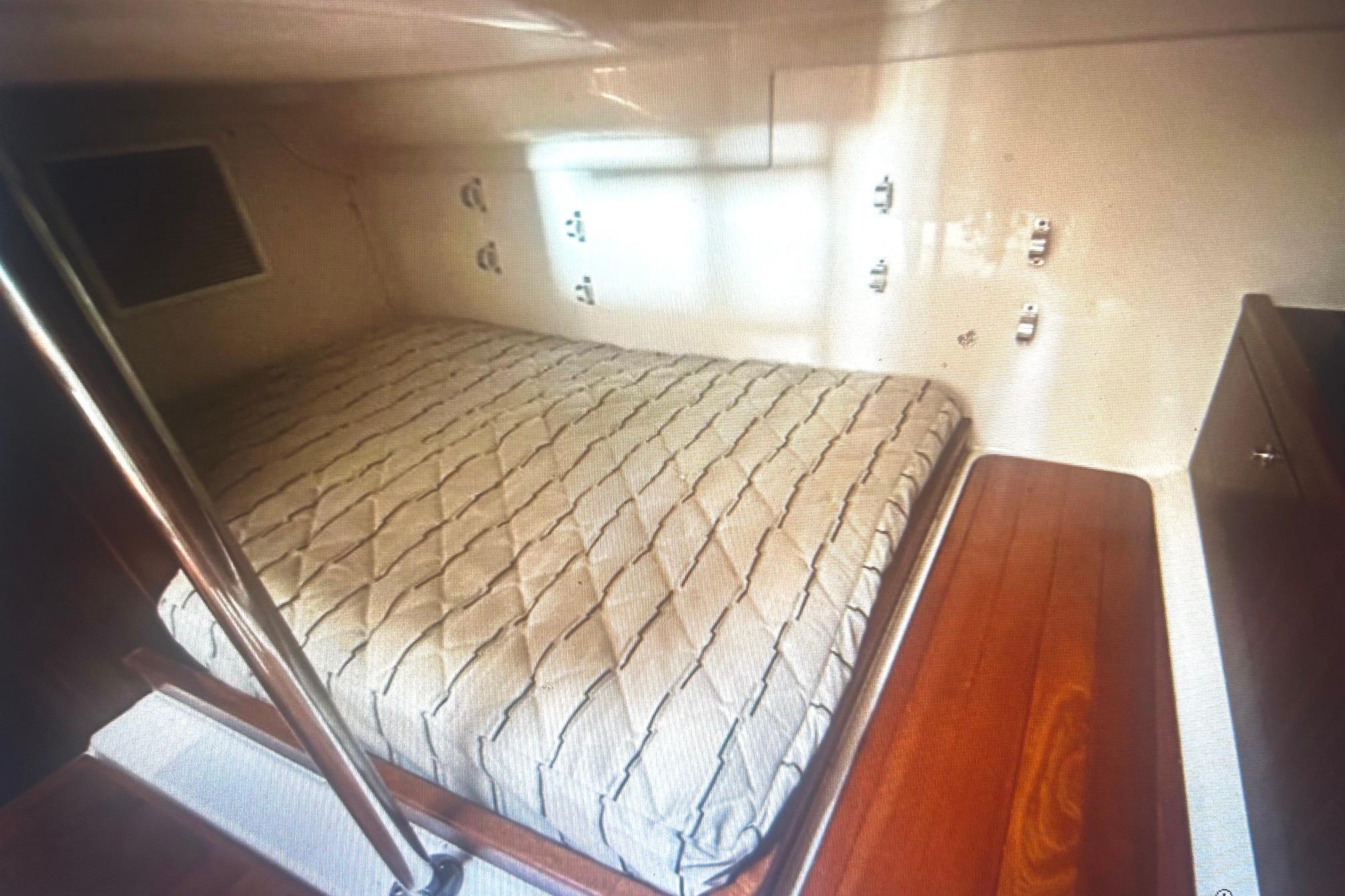 2019 Pursuit OS 355 Offshore cabin interior with bed and wooden accents.