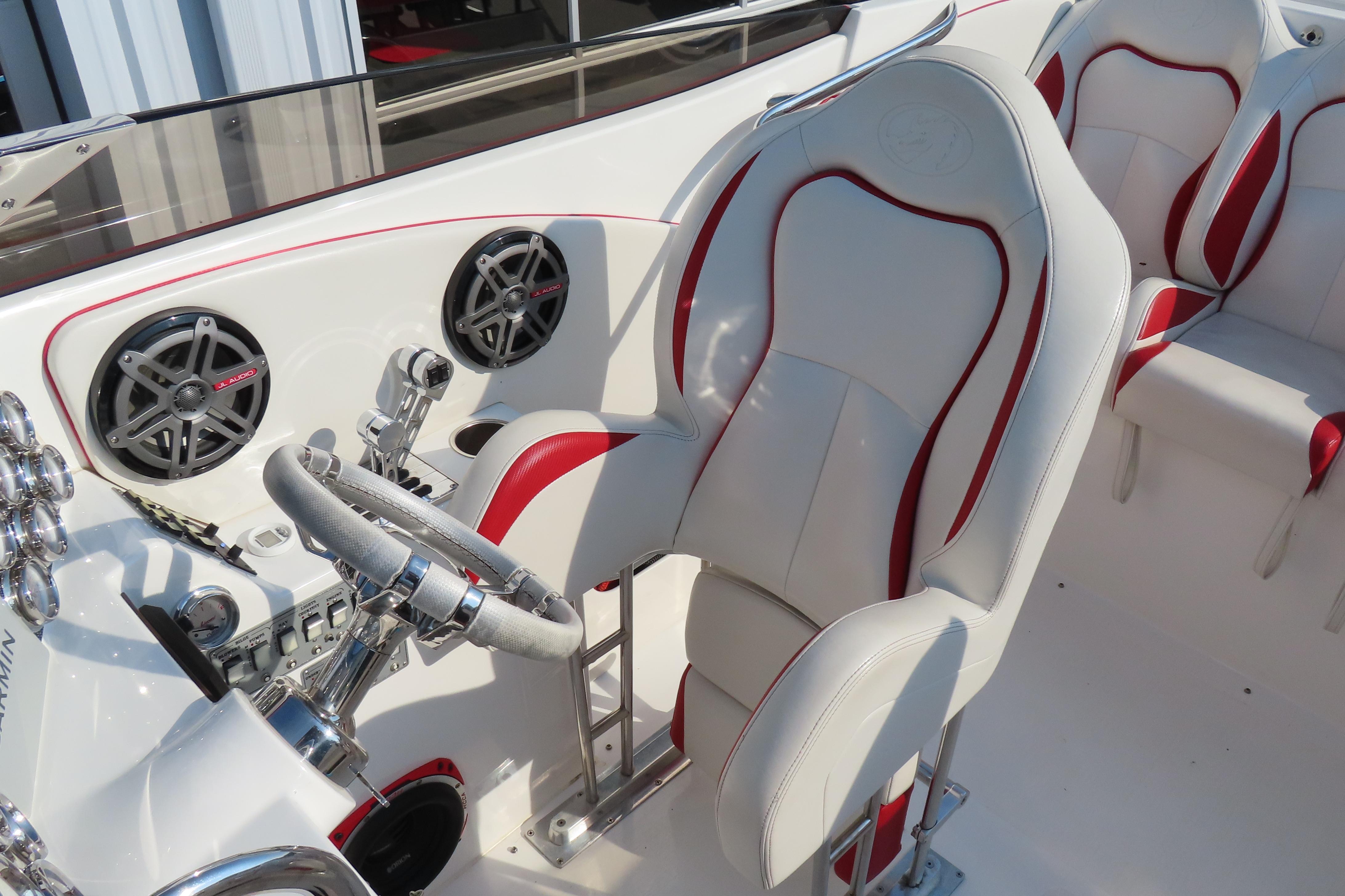 Interior of 2013 Nordic 39 POKER RUN boat with white and red seating, steering wheel, and speakers.