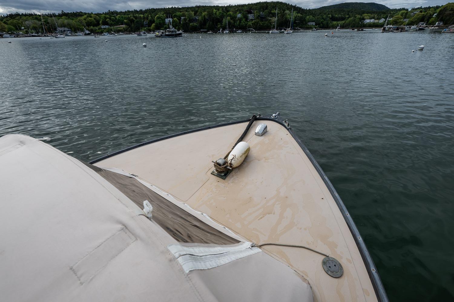 Bow view of 1989 Ellis 24 Open boat on calm water, surrounded by lush greenery.
