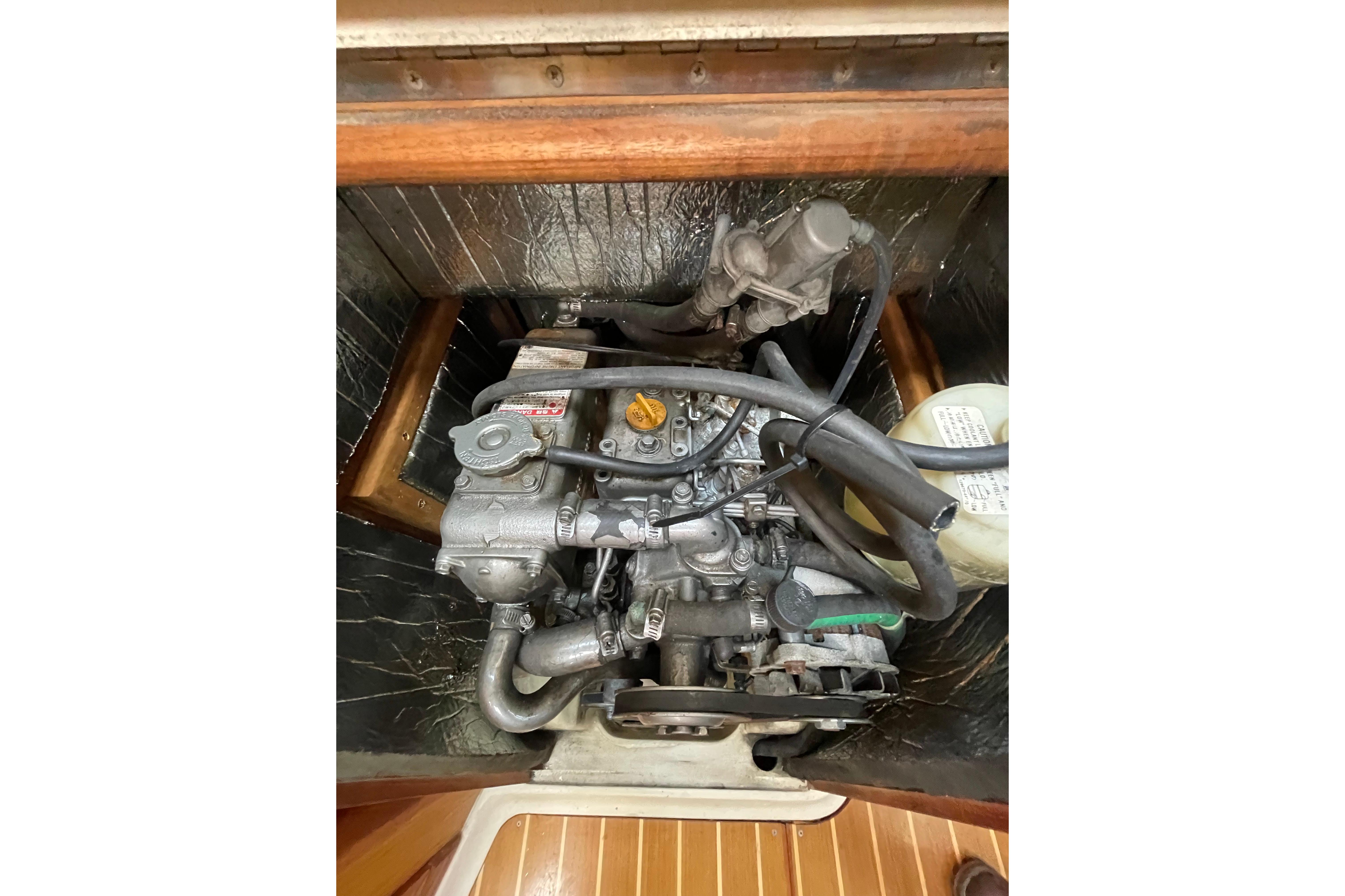 Engine compartment of a 2000 Hunter 340 sailboat, showcasing mechanical components and hoses.