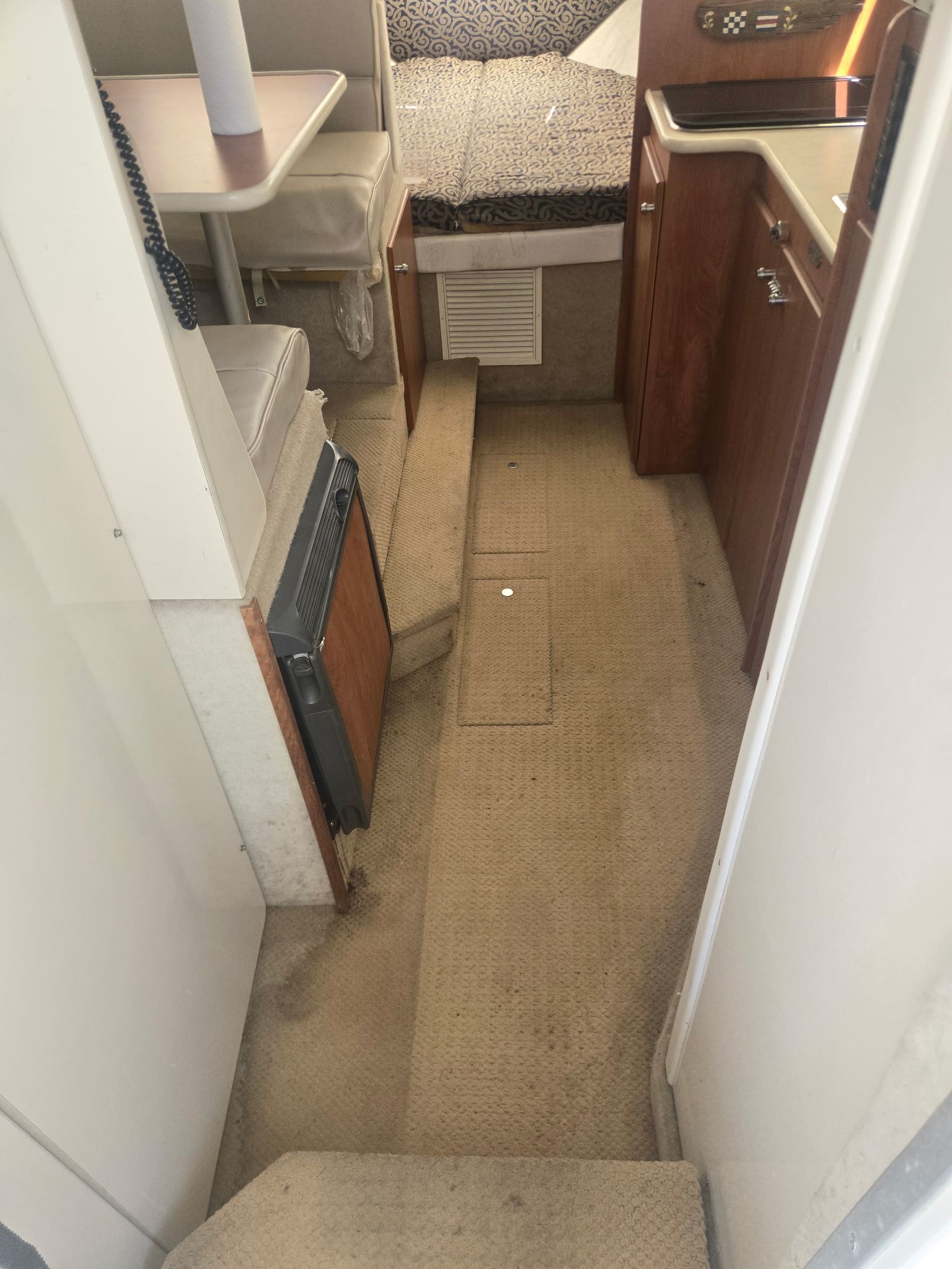 Interior of a 2003 Bayliner 28 with carpeted floor and wooden cabinetry.
