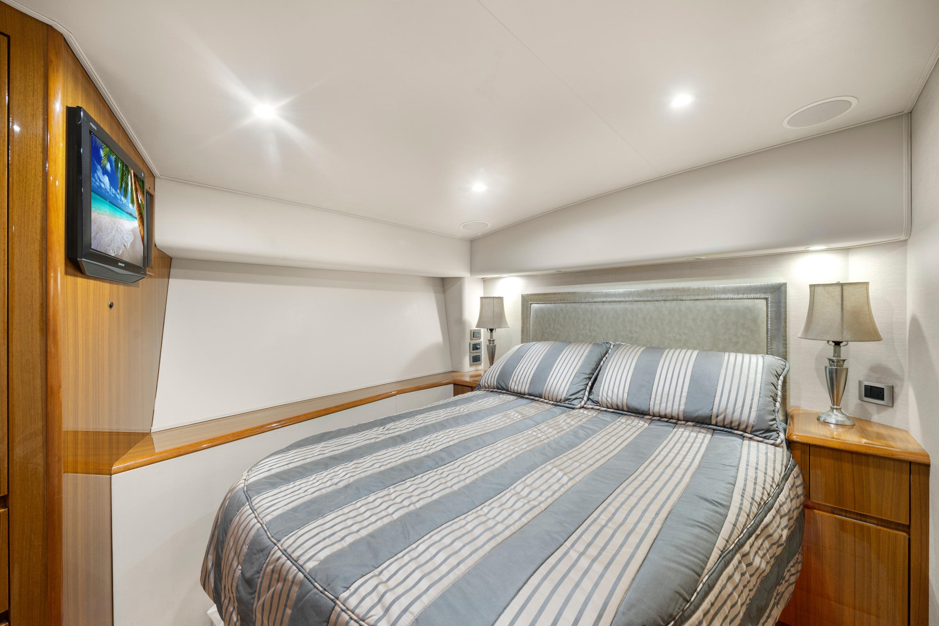 Luxurious bedroom interior of 2009 Viking 50 Convertible yacht with striped bedding and modern lighting.