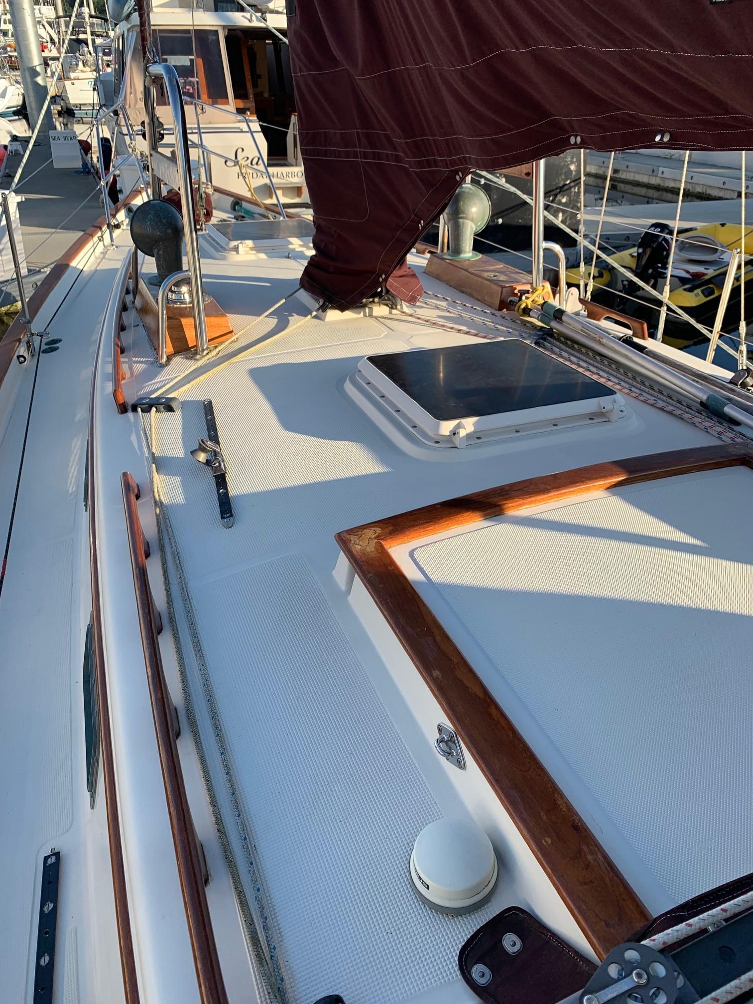1990 Pacific Seacraft 37 sailboat deck with wooden trim and hatch, docked at marina.
