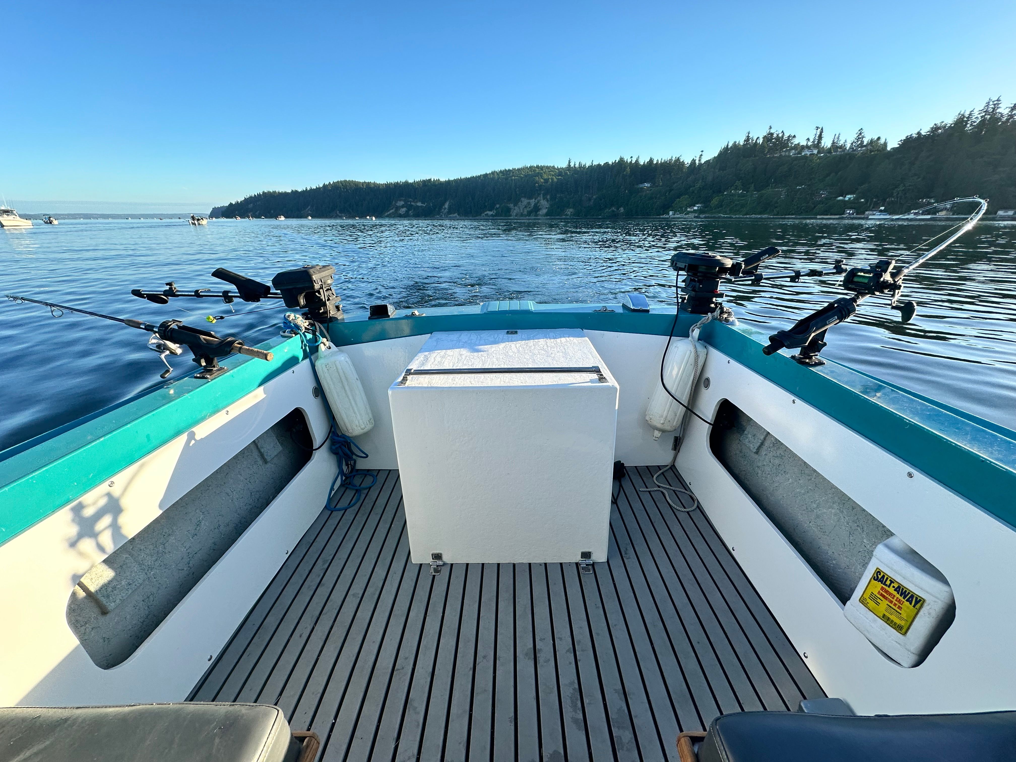 A restored 1967 Fiberform boat on calm water with fishing rod holders and a central storage unit.