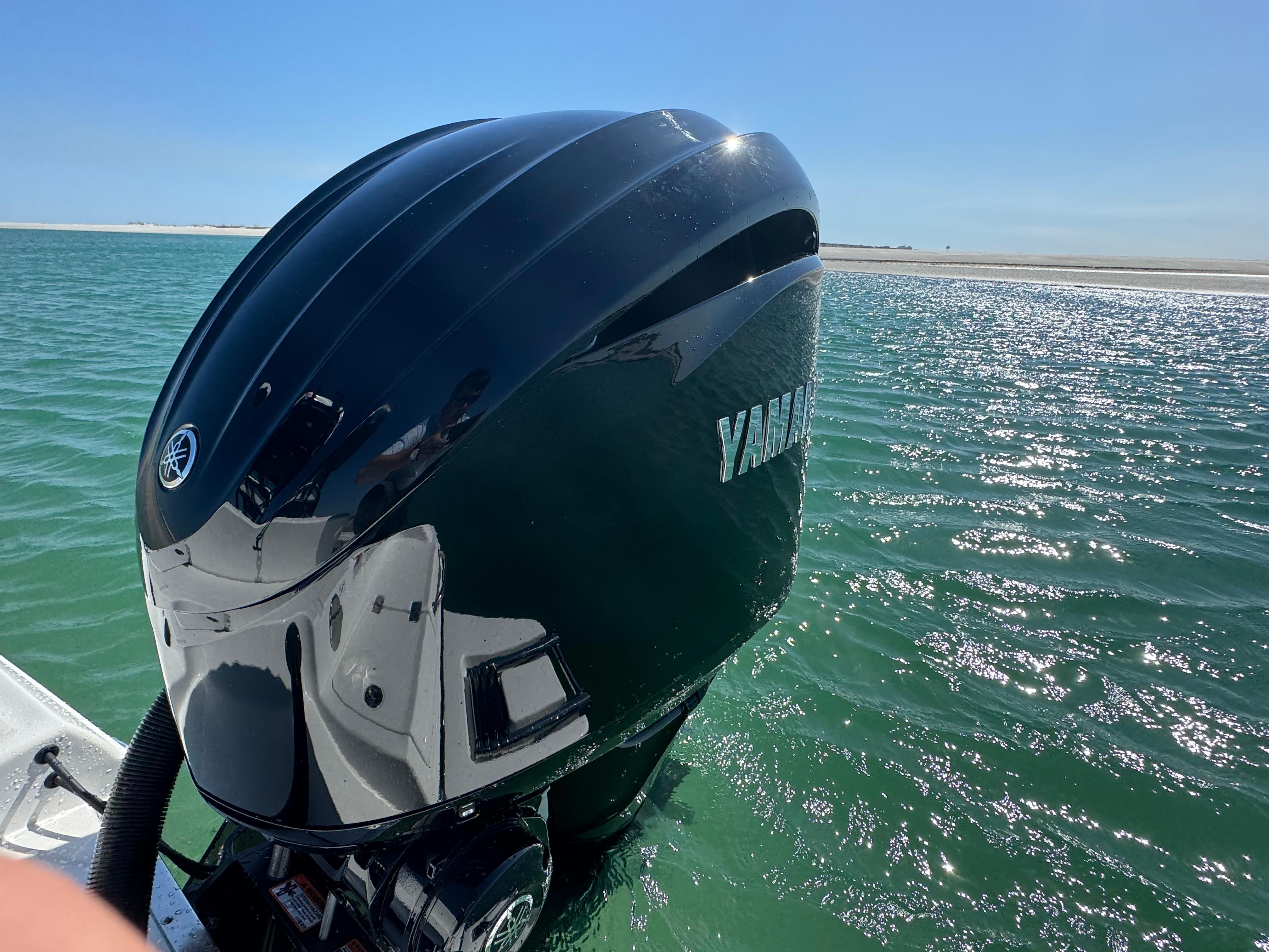 Outboard motor on a 2025 Crevalle 24 HCO boat in clear blue water.
