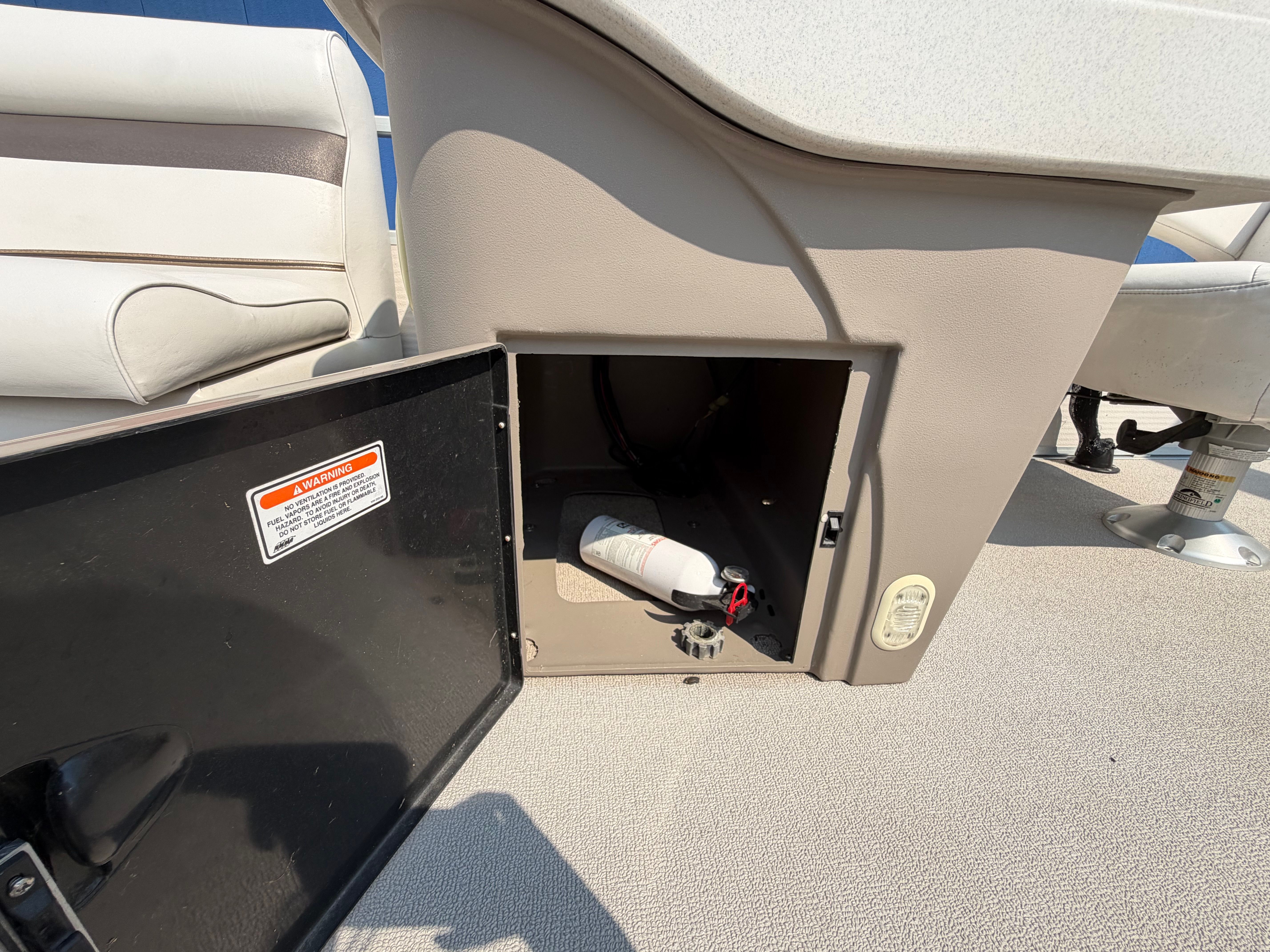 An open storage compartment on a boat with a fire extinguisher inside.