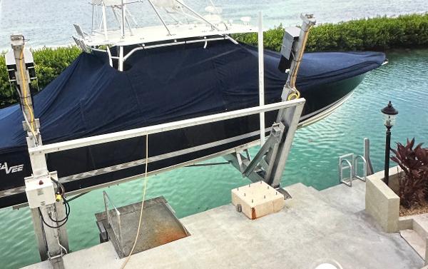 2008 SeaVee 390B boat on lift, covered, near turquoise water and dock.