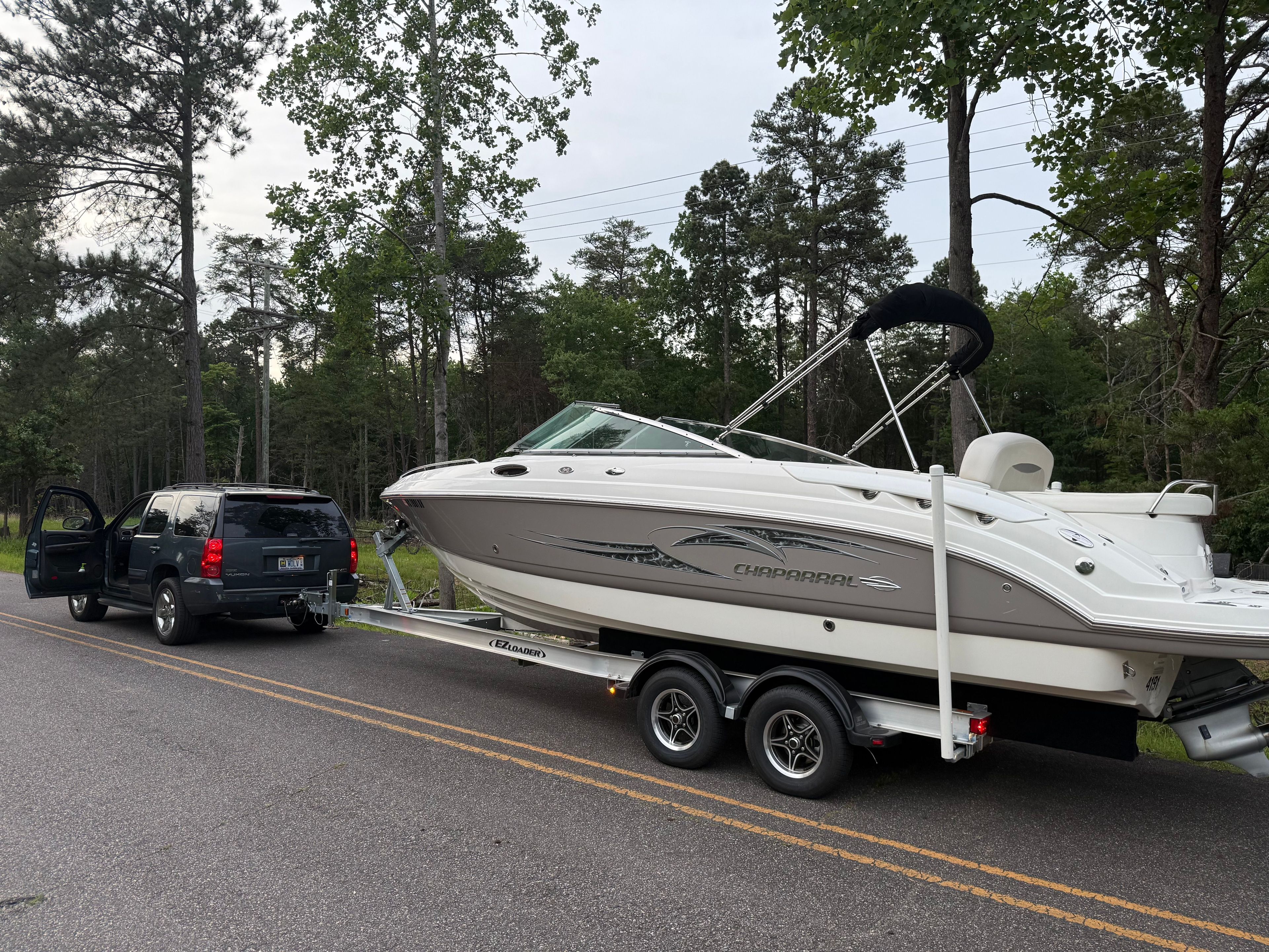 A 2007 Chaparral 256 SSX boat on a trailer, towed by a black SUV on a road.