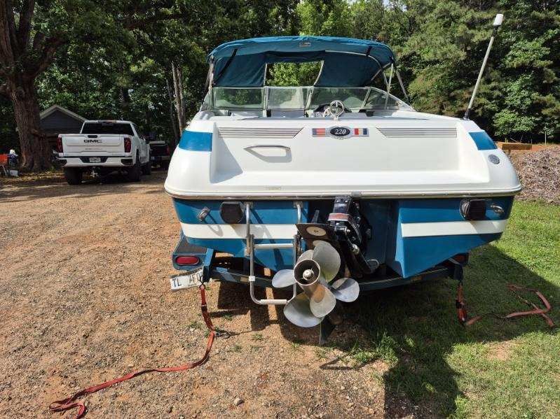 A 1996 Cobalt 220 boat on a trailer in a wooded area.