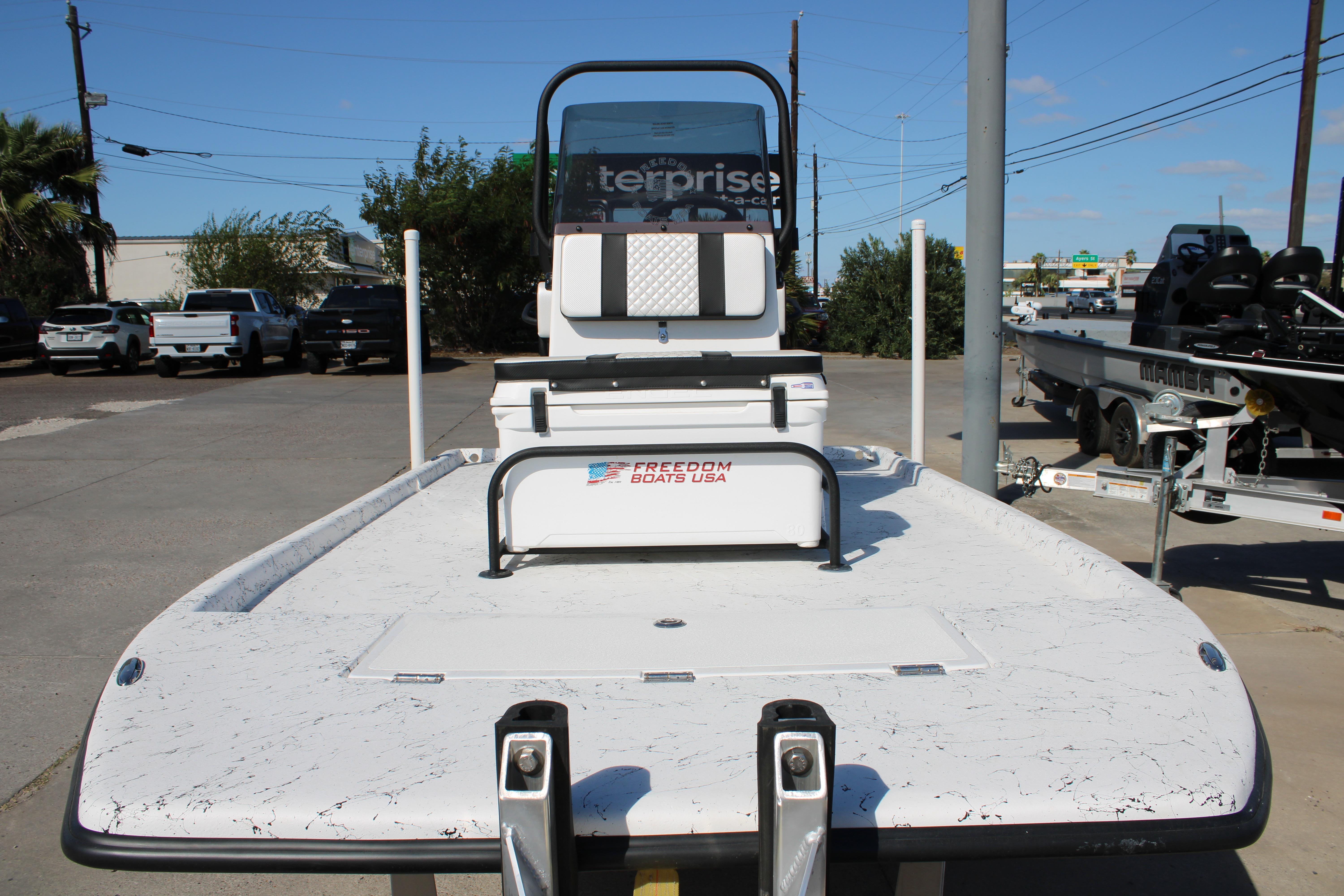 2026 Freedom Boats Chiquita, white deck, parked outdoors, showcasing sleek design and modern features.