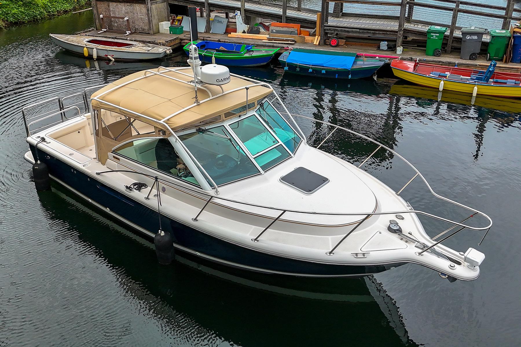 2006 Tiara Yachts 2900 Coronet docked in a marina, surrounded by colorful boats.