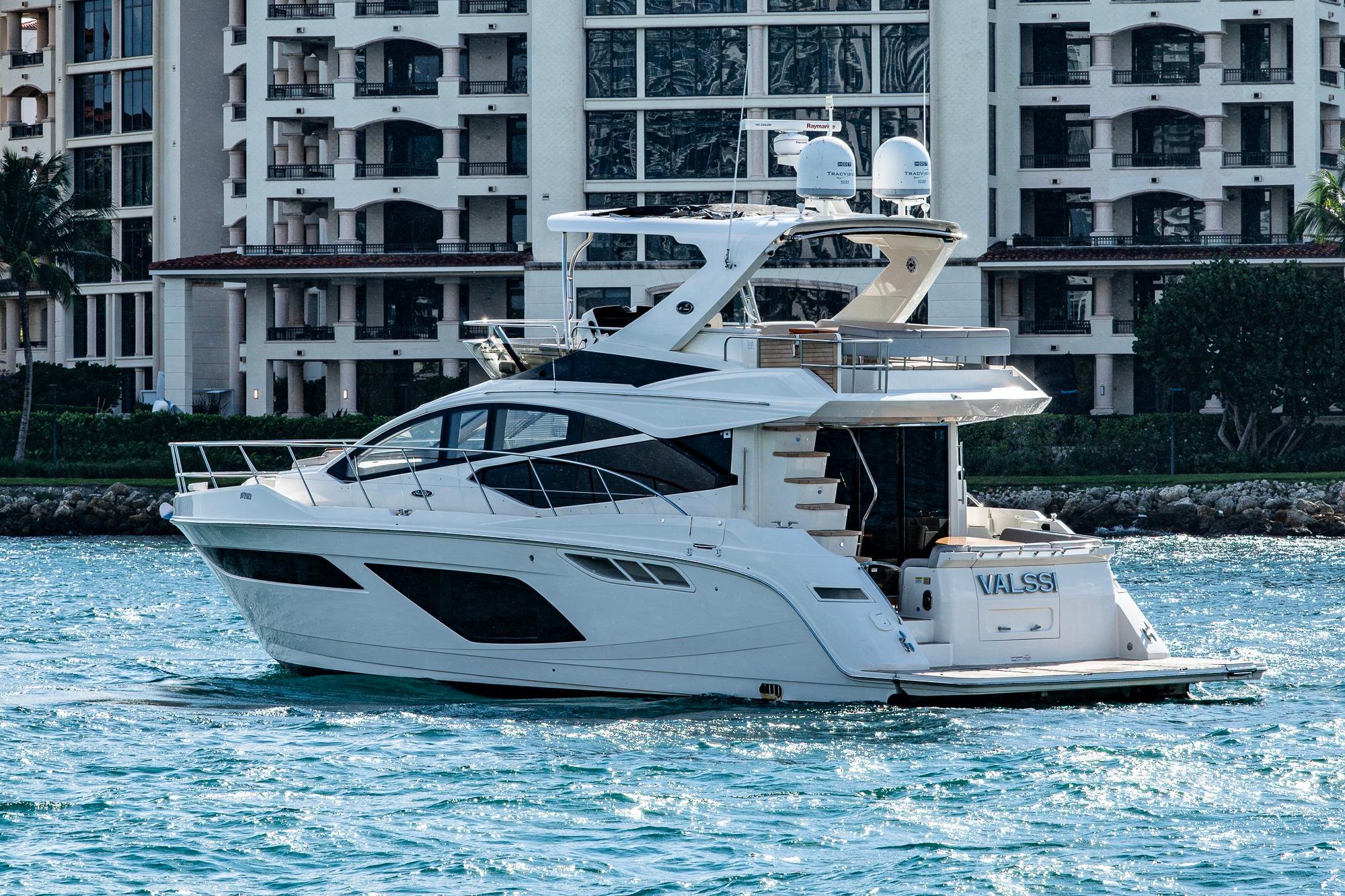 2018 Sea Ray L550 Fly yacht cruising near luxury waterfront buildings.