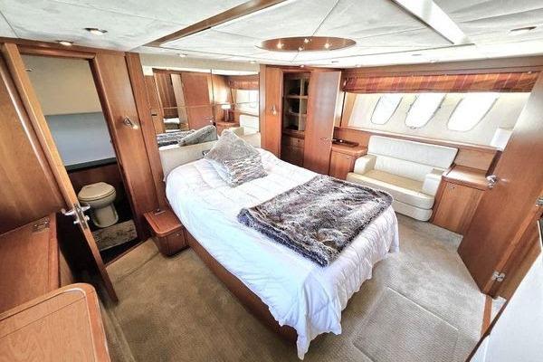 Luxurious bedroom interior of 2005 Sunseeker Manhattan 66 yacht with elegant wood finishes.