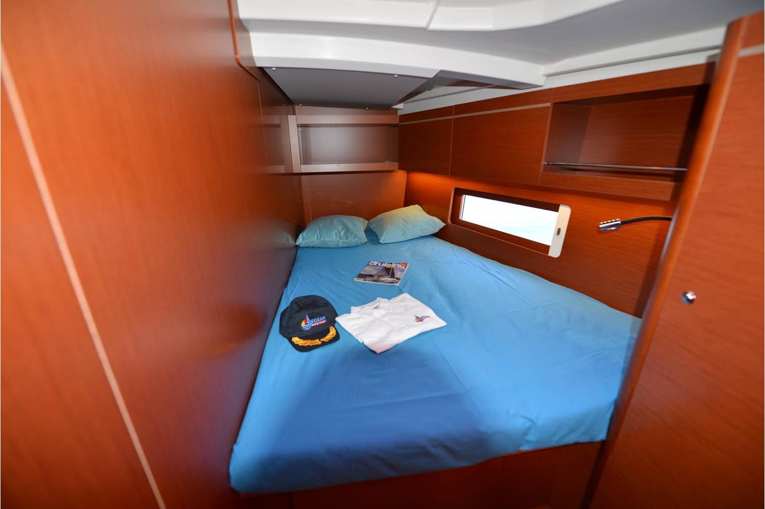 Cozy cabin interior of 2019 Beneteau Oceanis 46.1 yacht with blue bedding and wooden finish.