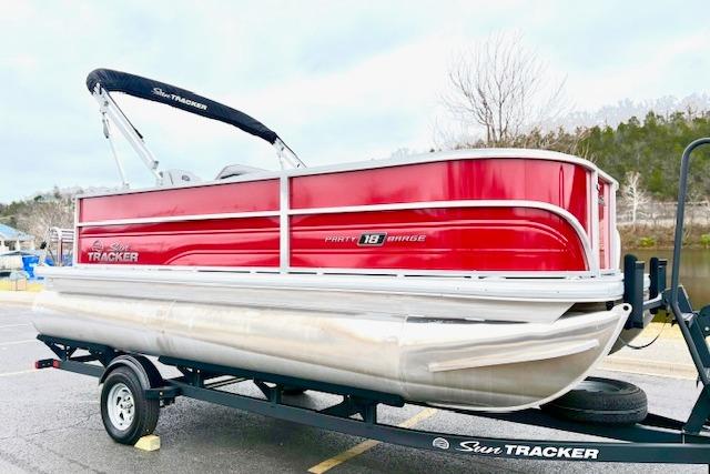 2026 Sun Tracker Party Barge 18 DLX pontoon boat on trailer, red and silver design.