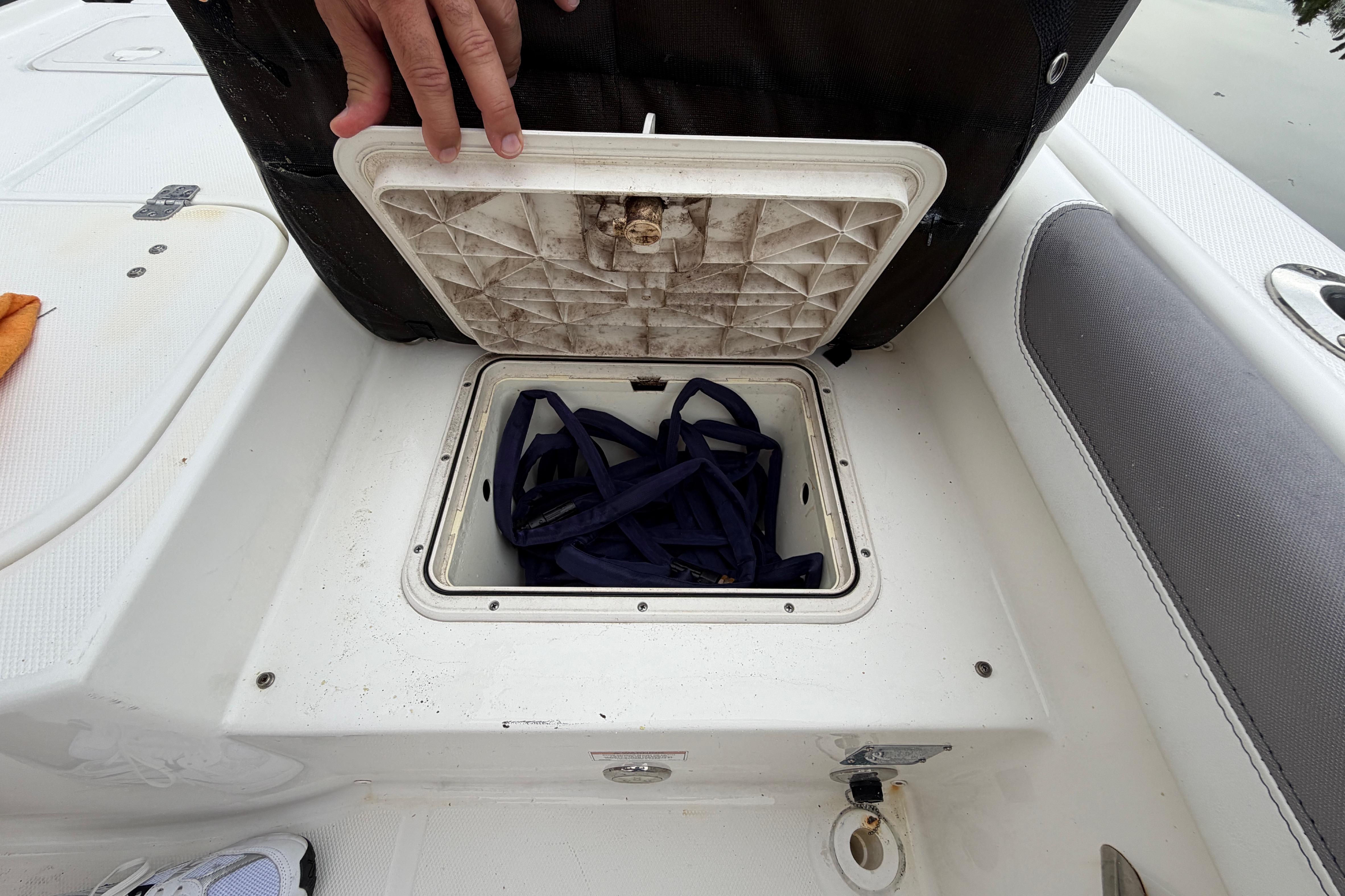 Open storage compartment on a 2019 World Cat 230 DC boat, revealing blue straps inside.