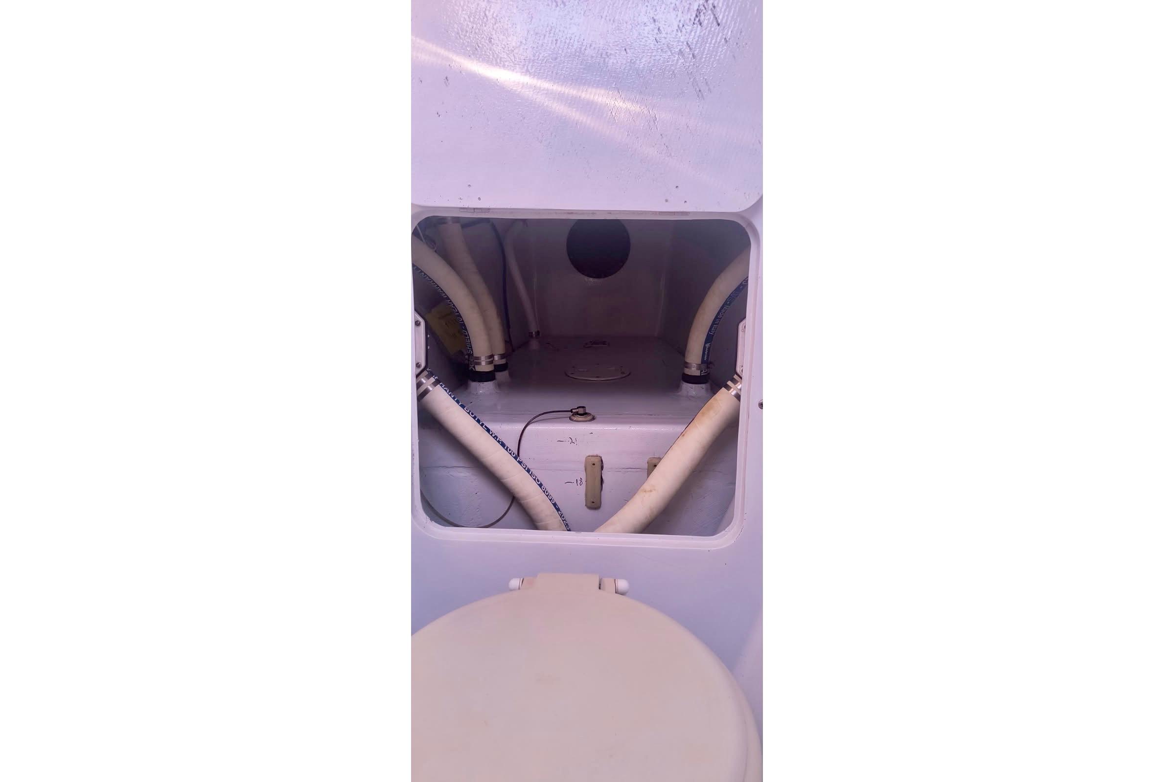 Interior view of a 2012 Hughes 40 boat showing plumbing and storage compartment.
