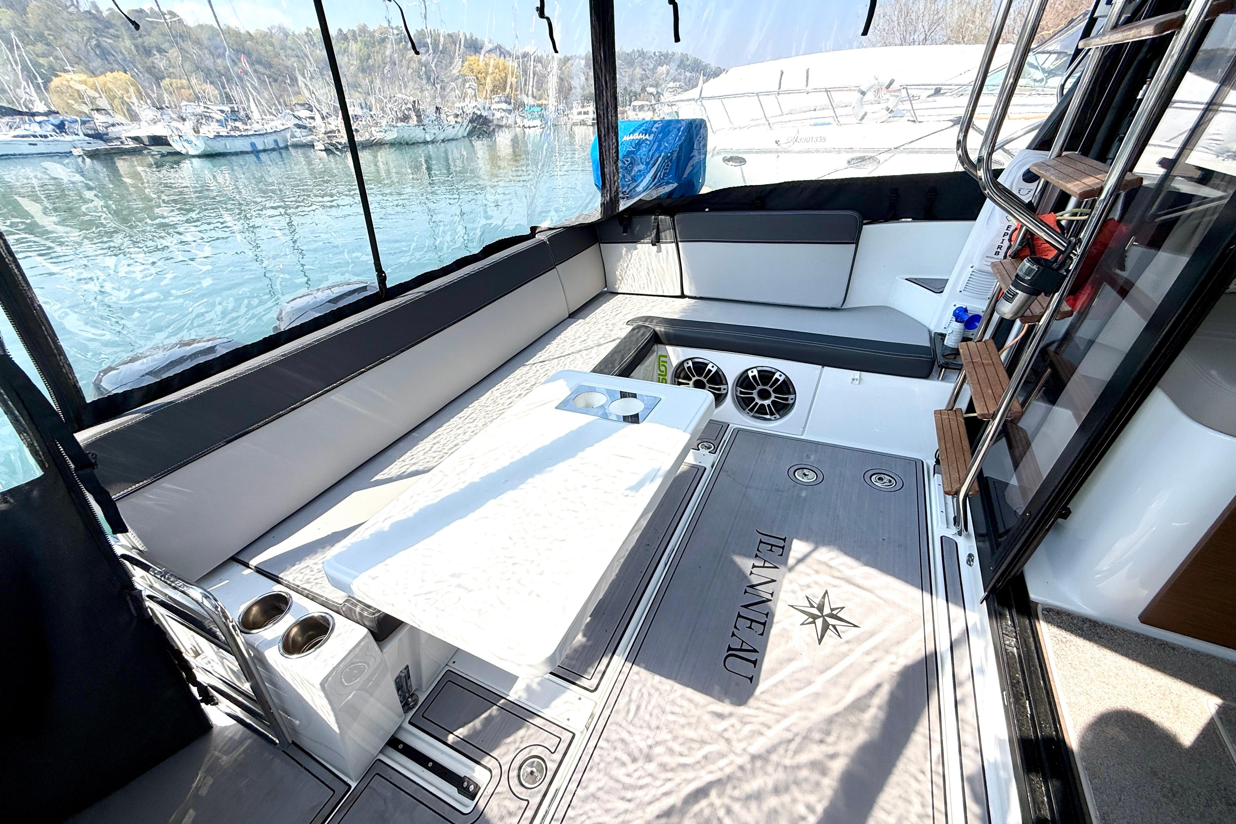 2022 Jeanneau NC 1095 Fly cockpit with seating, table, and scenic marina view.
