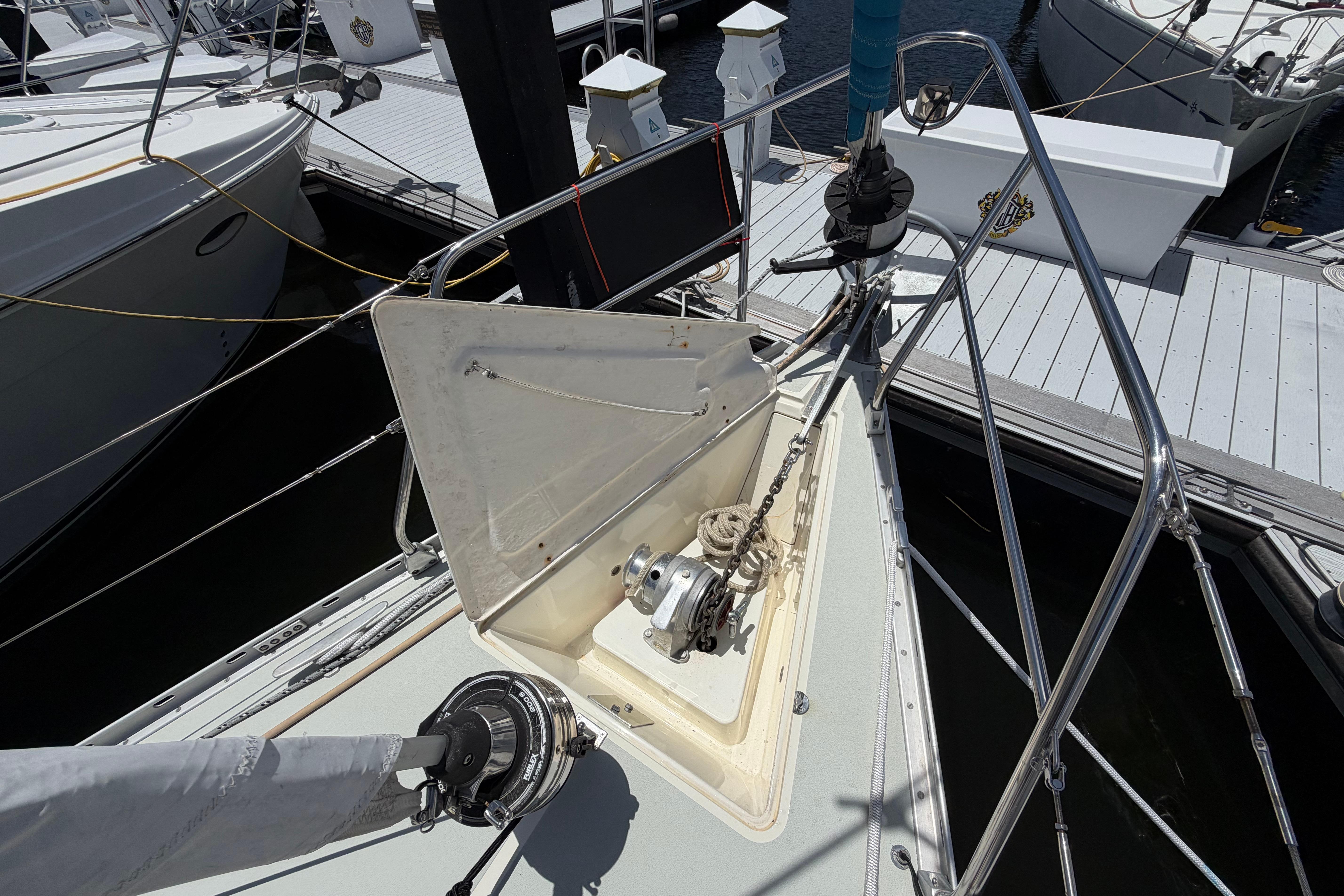 Bow of 1987 Moody 376 sailboat with anchor chain and winch at marina.
