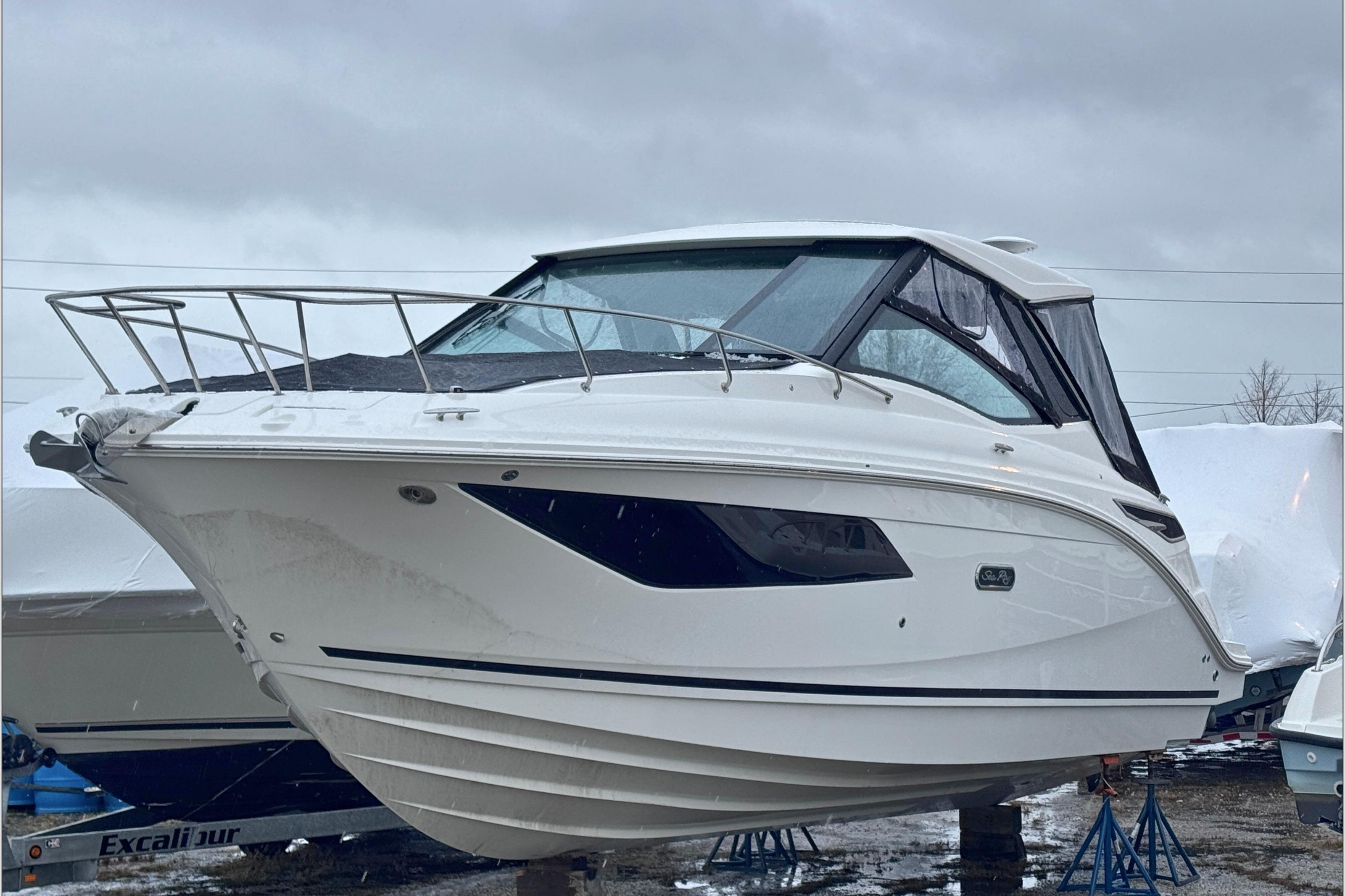 2025 Sea Ray Sundancer 320 boat on stands, overcast sky background.