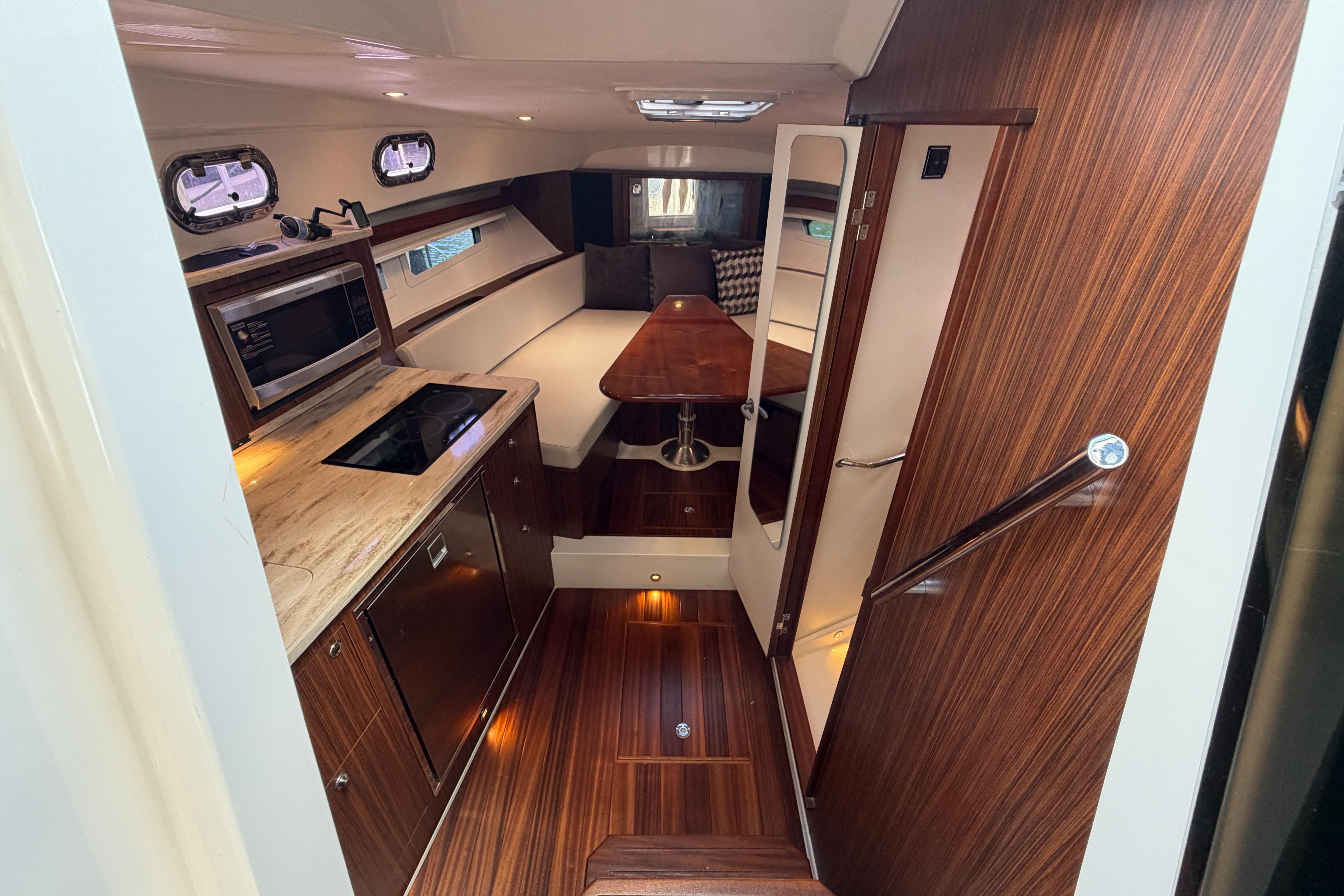 Luxurious interior of a 2018 Pursuit OS 355 Offshore boat with modern kitchen and seating area.