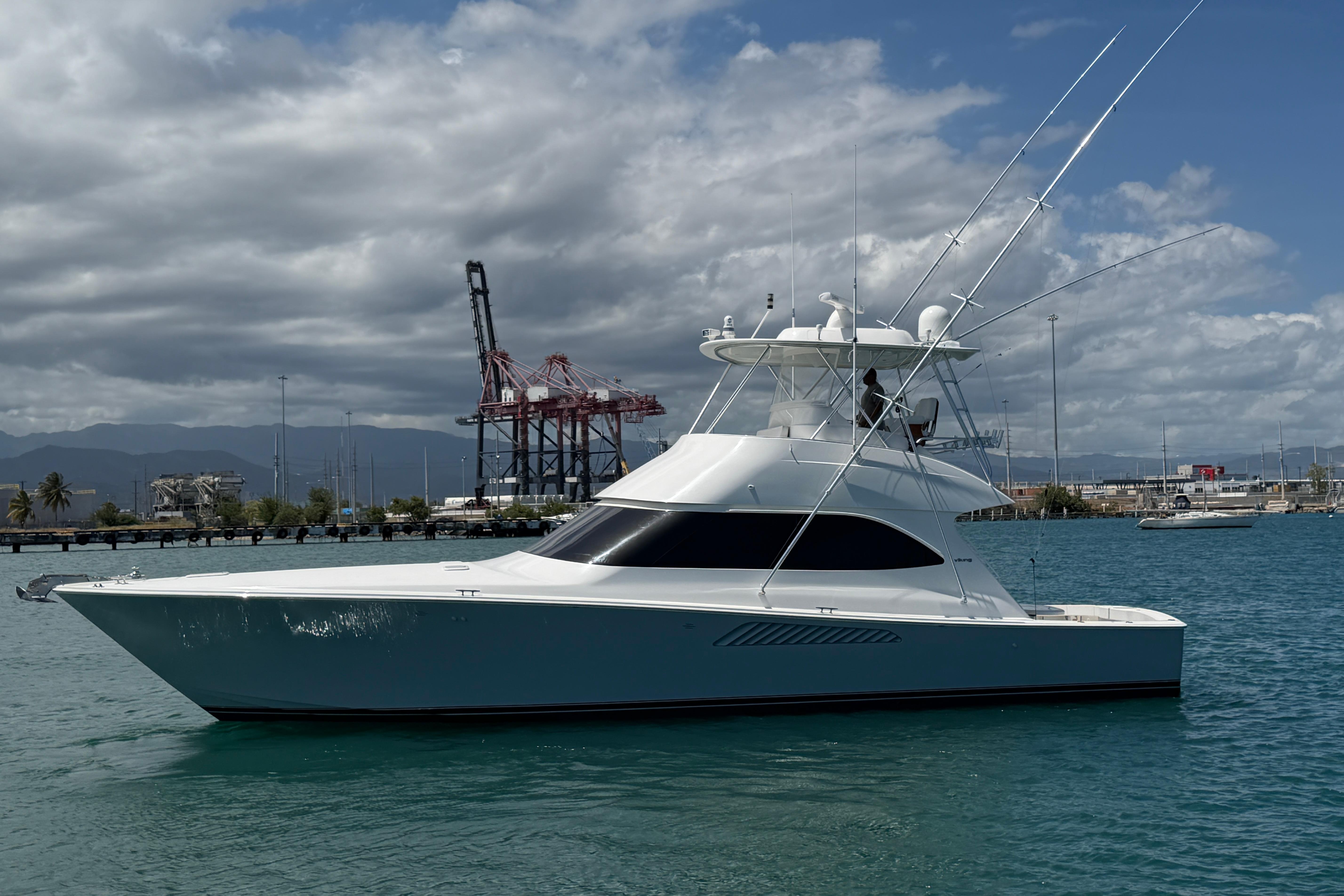 2012 Viking 50 Convertible yacht on calm water, with industrial background and cloudy sky.