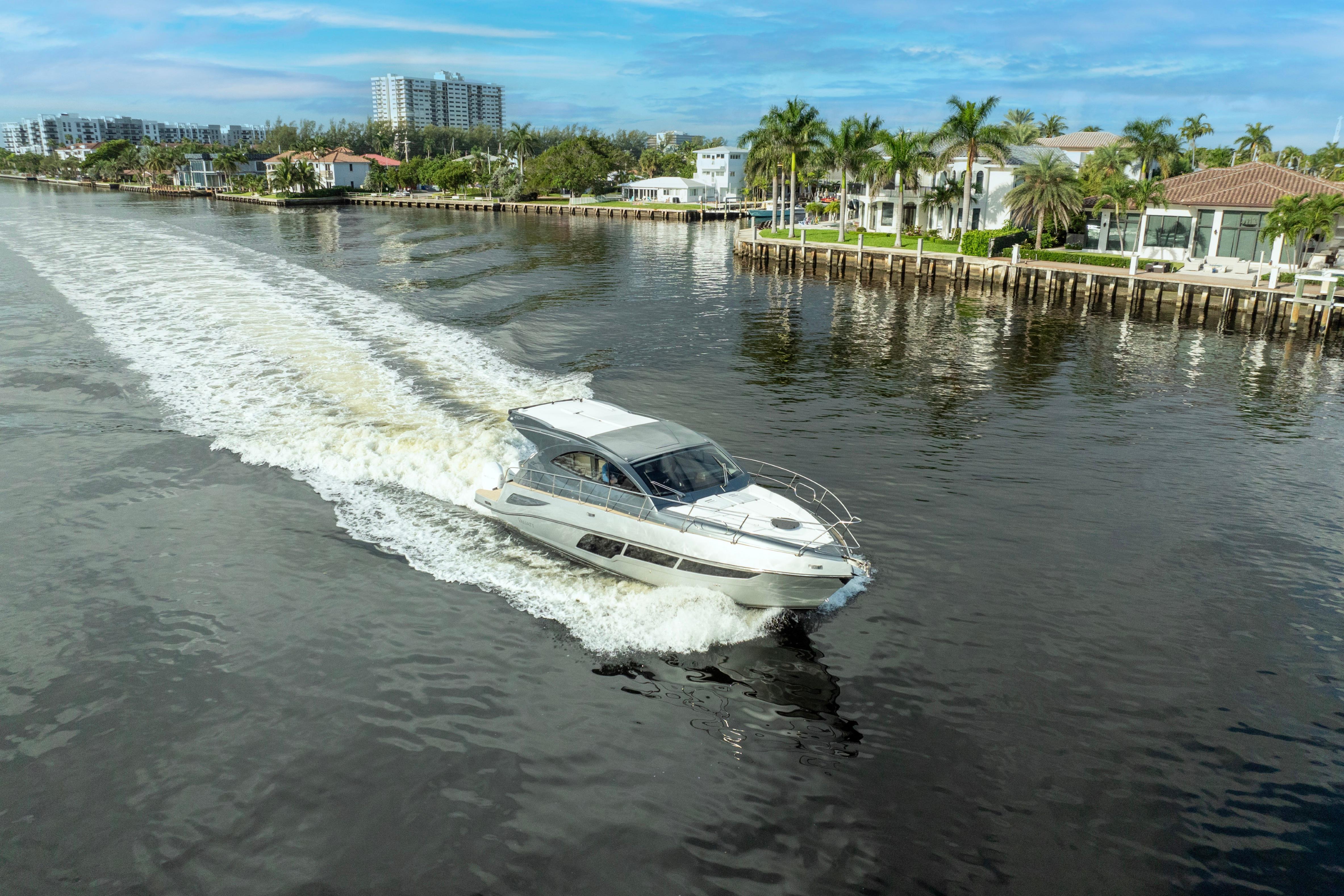 2025 Valiatt 410HT yacht cruising on a scenic waterway with waterfront homes.