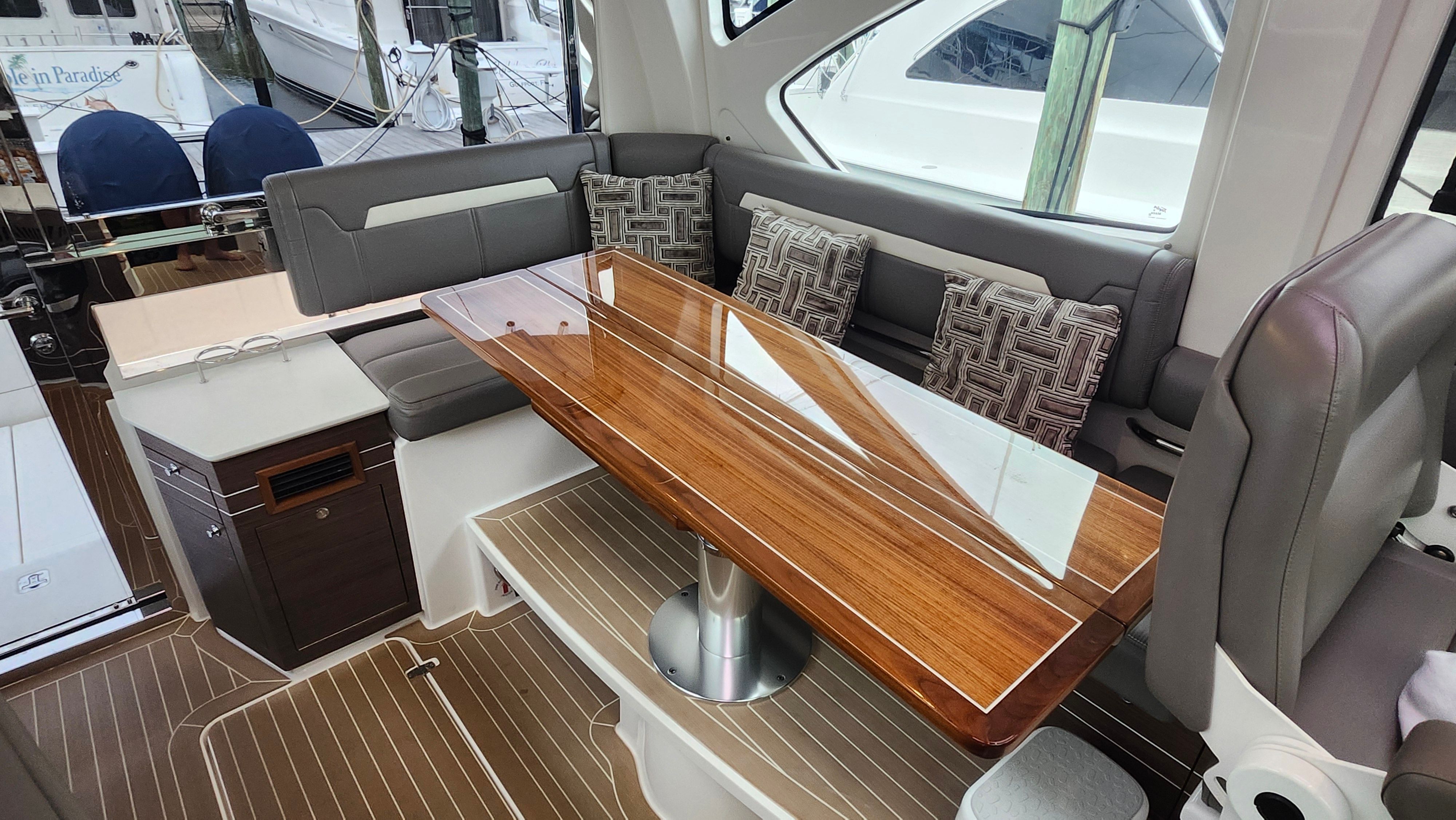 Interior of a Pursuit OS 445 Offshore with elegant wooden table and cushioned seating.