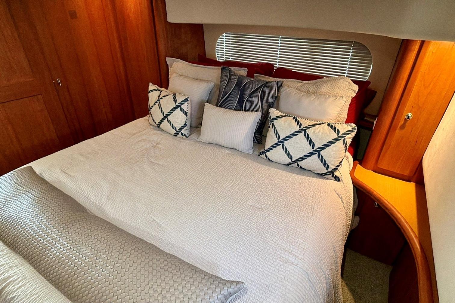 Luxurious bedroom interior of 2004 Silverton 39 Motor Yacht with plush bedding and wooden accents.