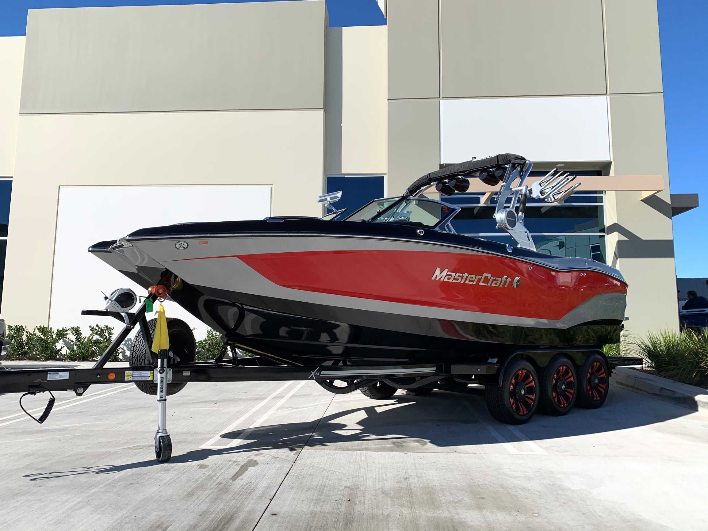 A 2020 MasterCraft X24 boat on a trailer in front of a modern building.