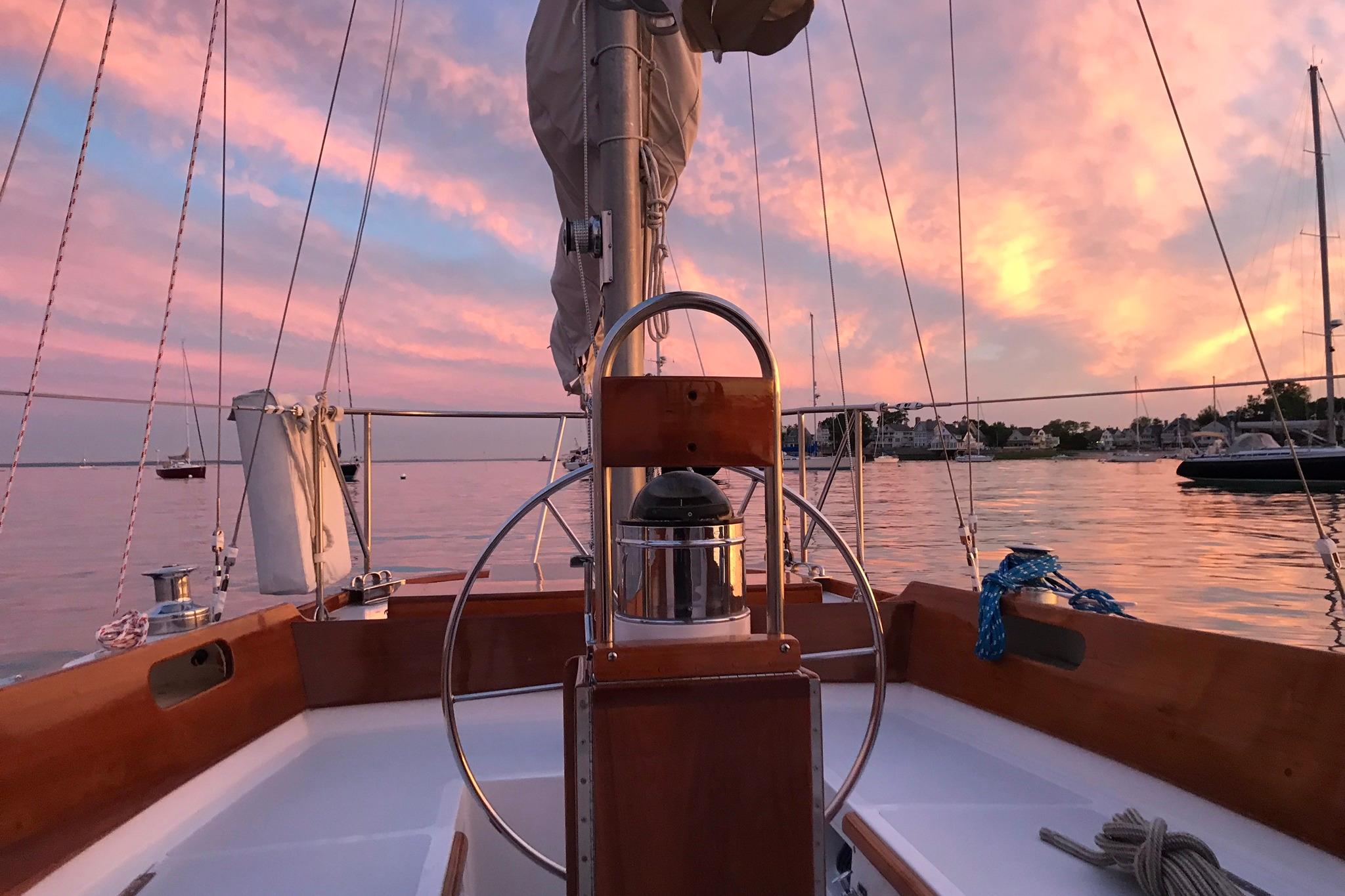 Hinckley Bermuda 40 sailboat at sunset, 1970 model, with vibrant pink sky and calm waters.