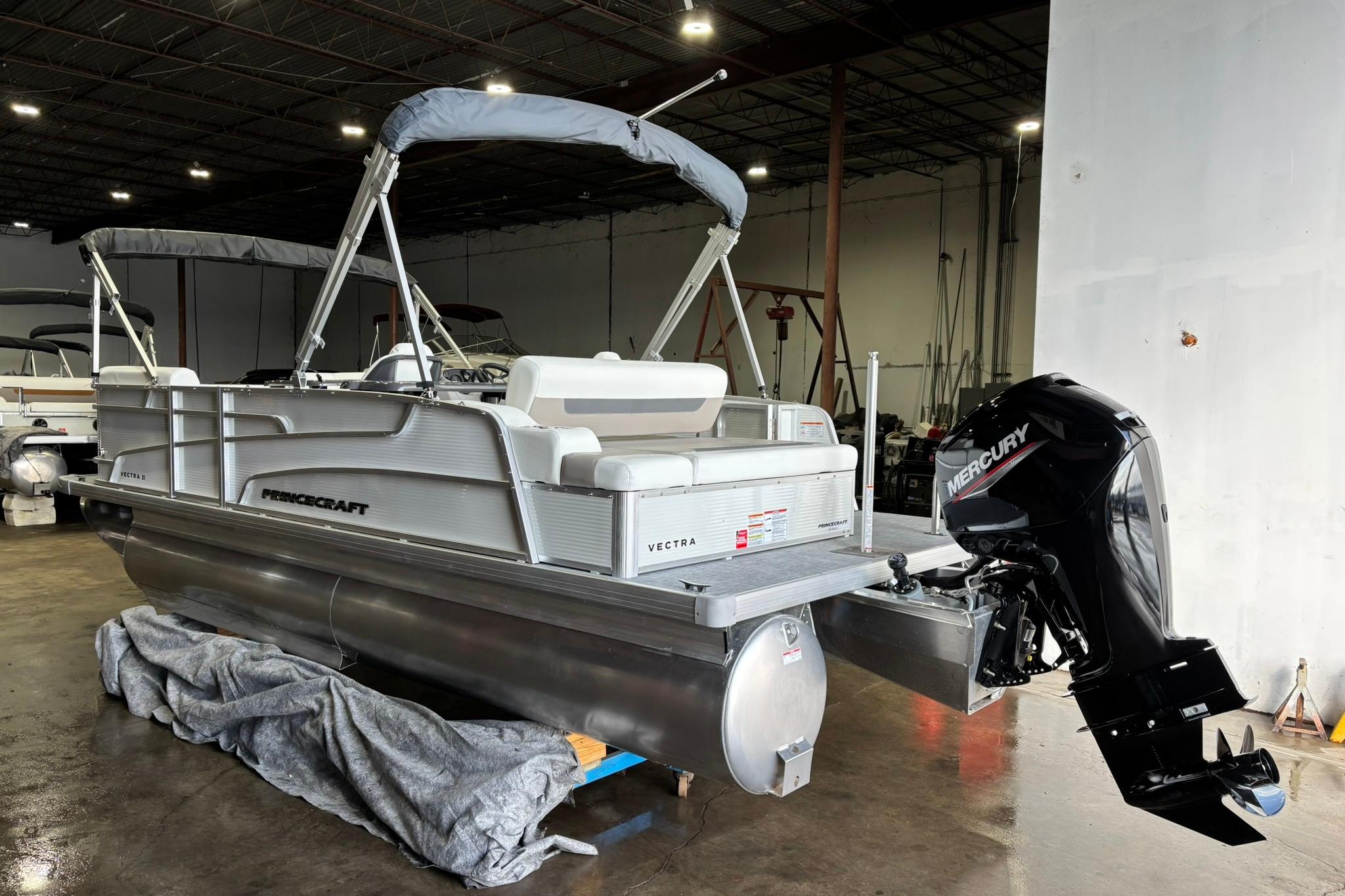 2025 Princecraft Vectra 21 RL pontoon boat with Mercury outboard motor in a warehouse.