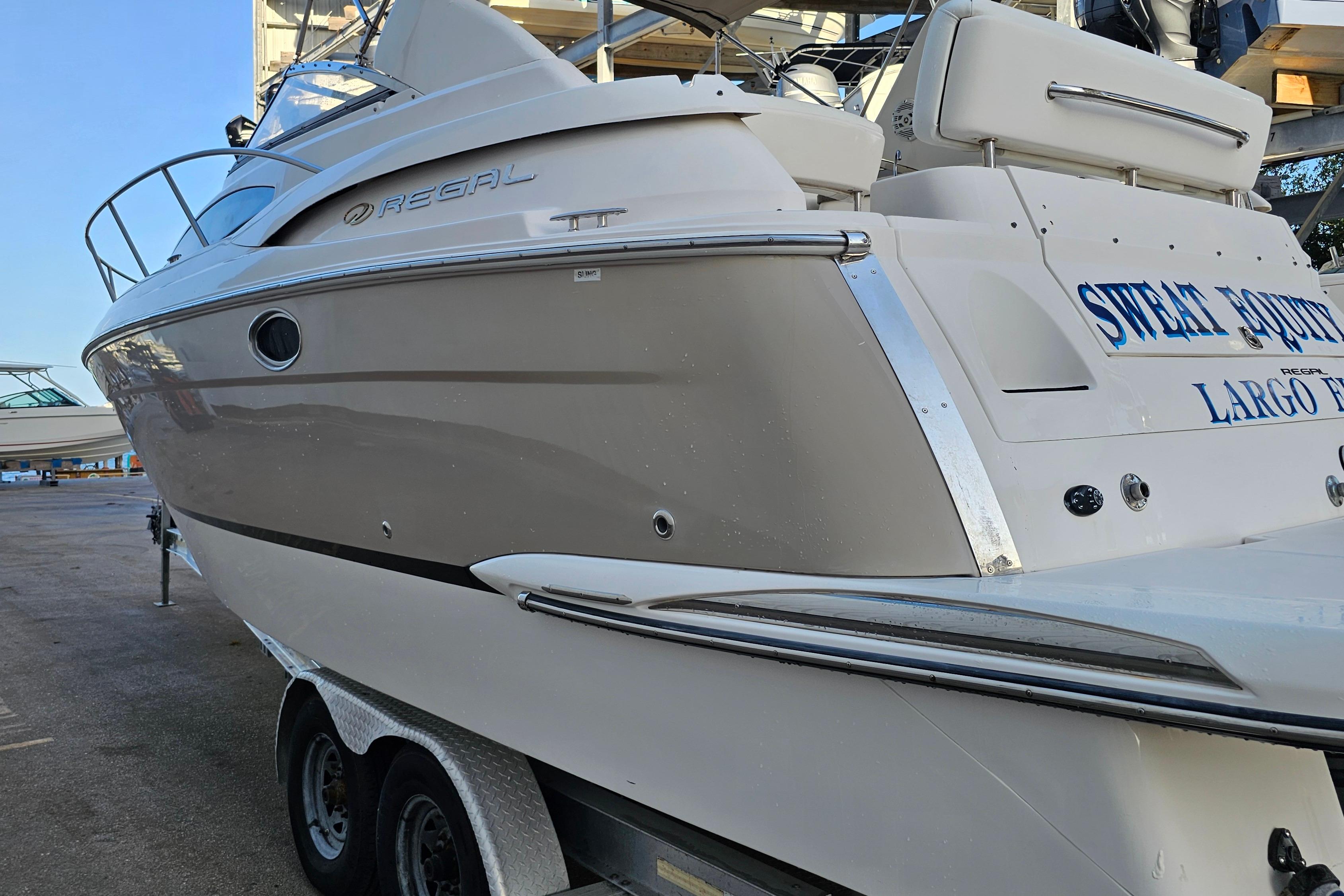 2005 Regal 3060 Window Express boat on trailer, side view, in a marina setting.