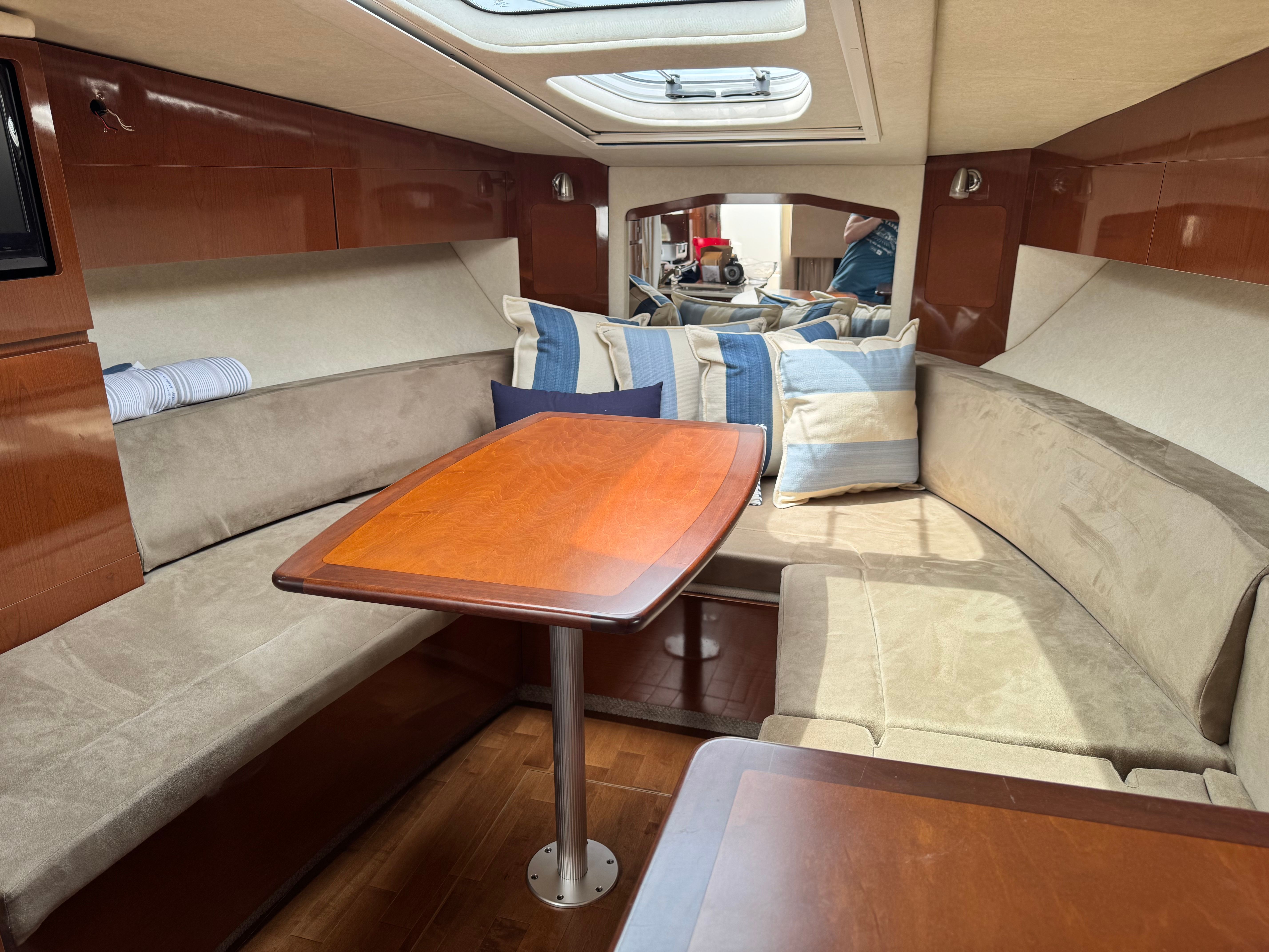Interior of a Sea Ray Sundancer 310 with cozy seating and a wooden table.