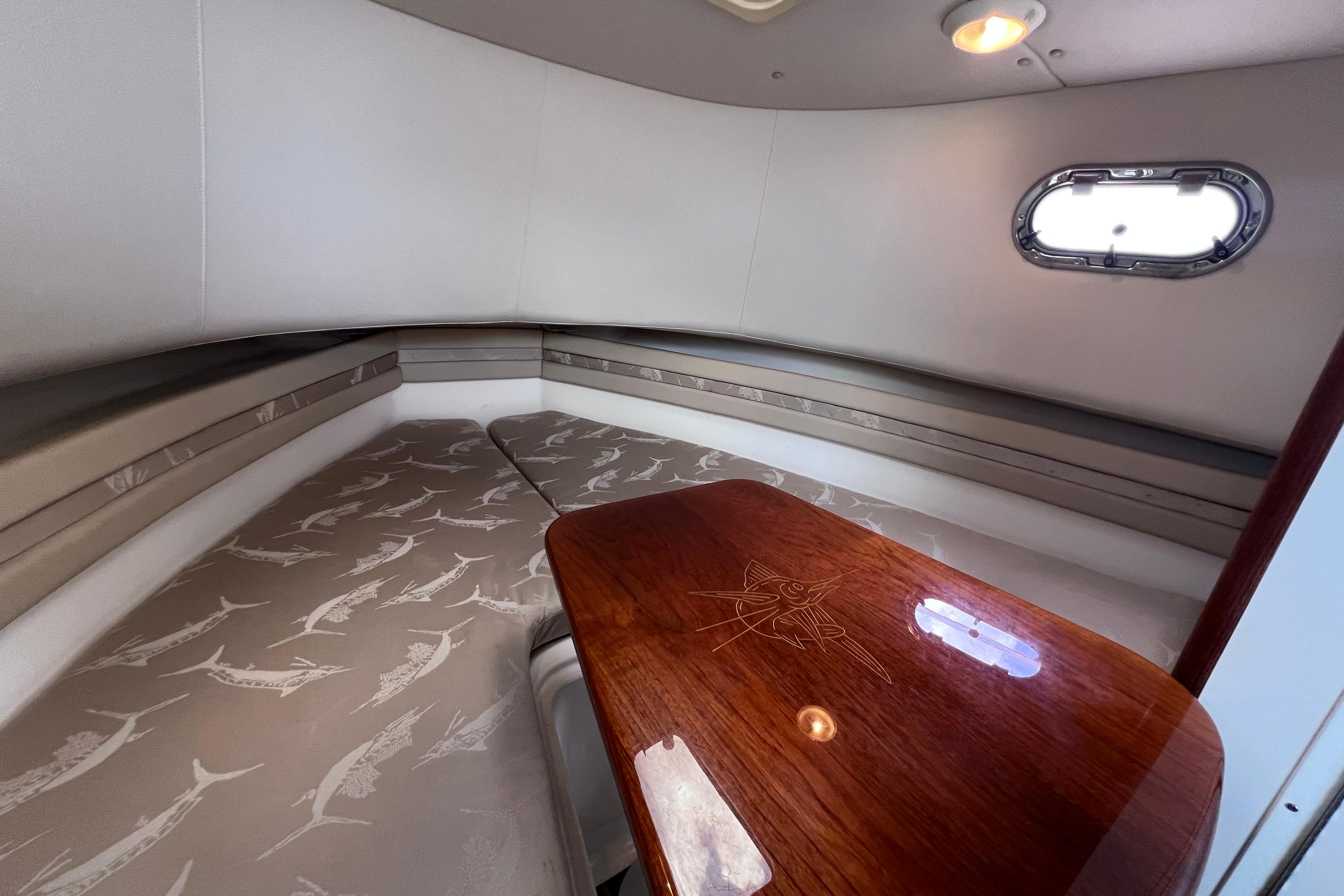 Interior cabin of 2004 Pursuit 2870 Walkaround boat with cushioned seating and wooden table.