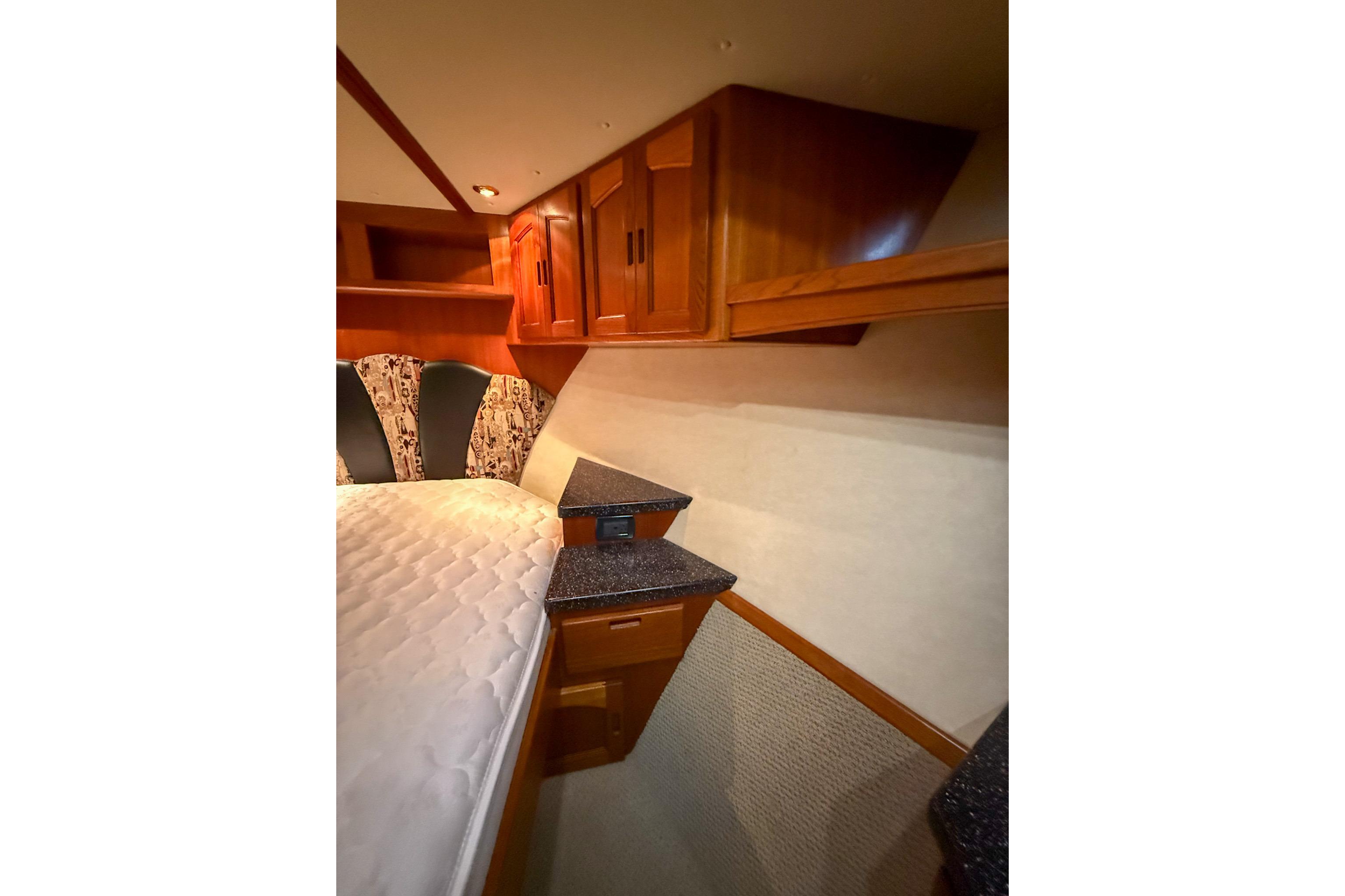 Cozy cabin interior of 2007 Nordic Tug 54 with wood cabinetry and comfortable bedding.