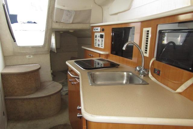 2002 Bayliner 2655 Ciera Sunbridge interior with kitchenette, sink, and stairs.