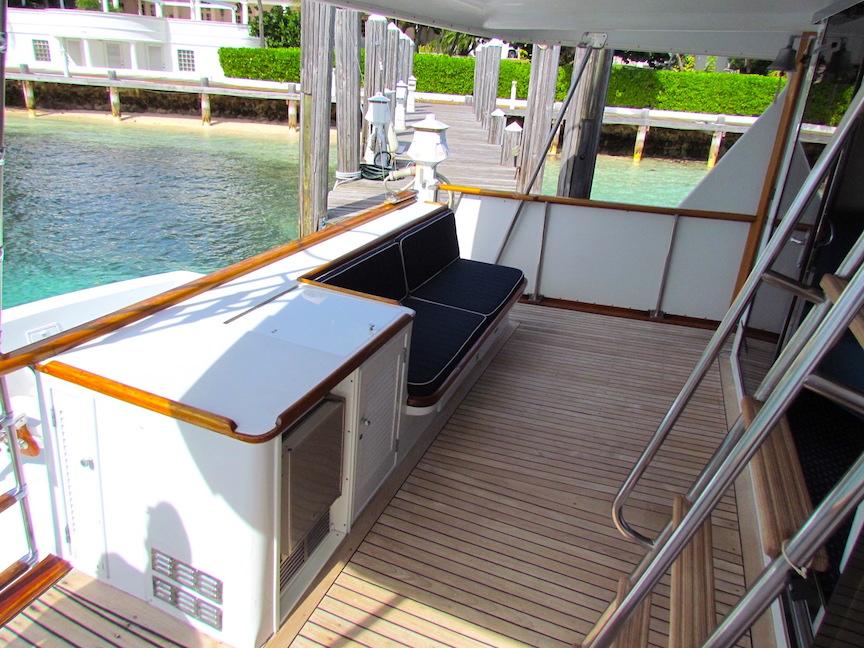 1972 Hargrave 67 Motor Yacht deck with seating, wooden flooring, and dockside view.