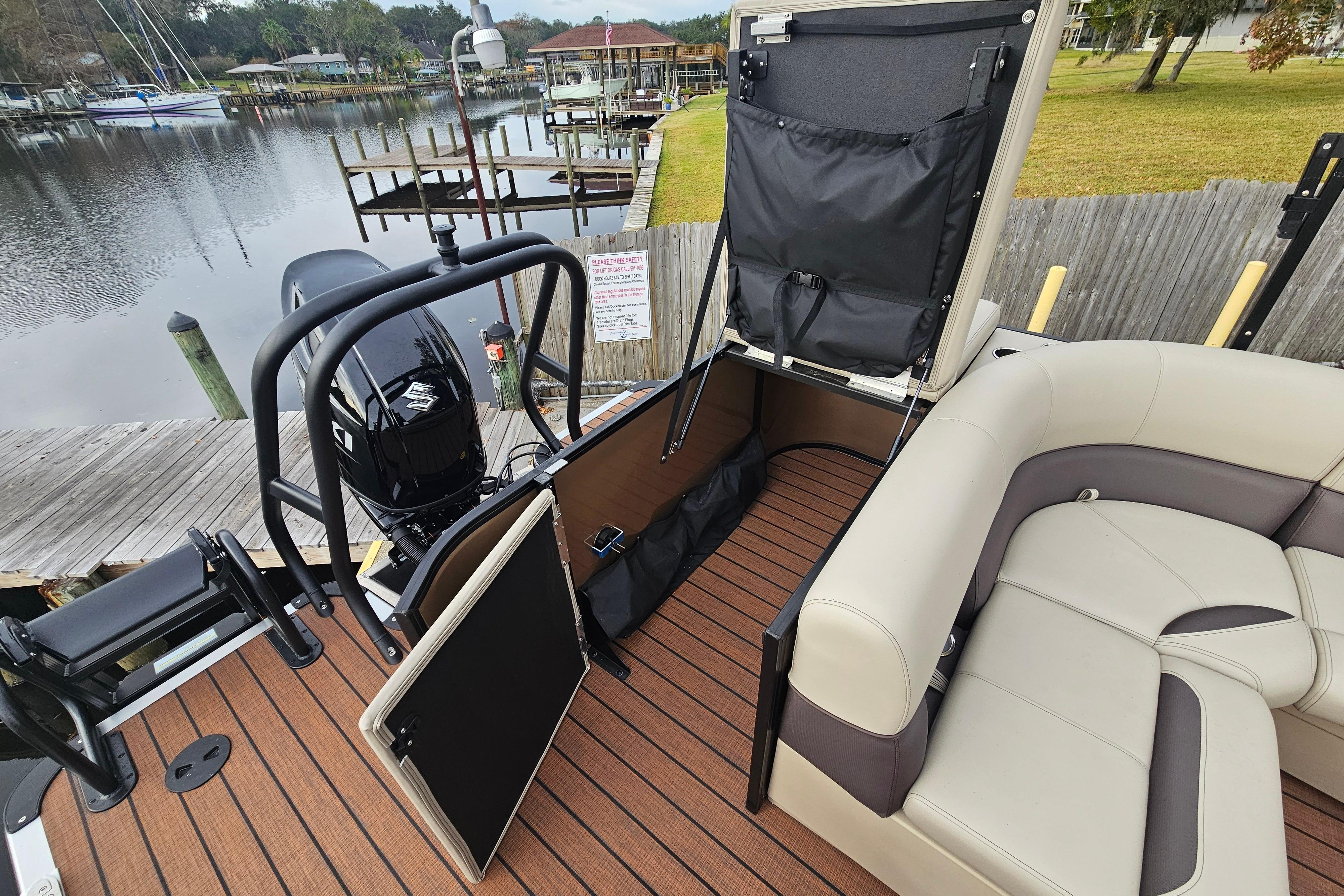 2026 Bentley Pontoons Legacy 243 Cruise interior with seating and storage, docked by a serene lake.