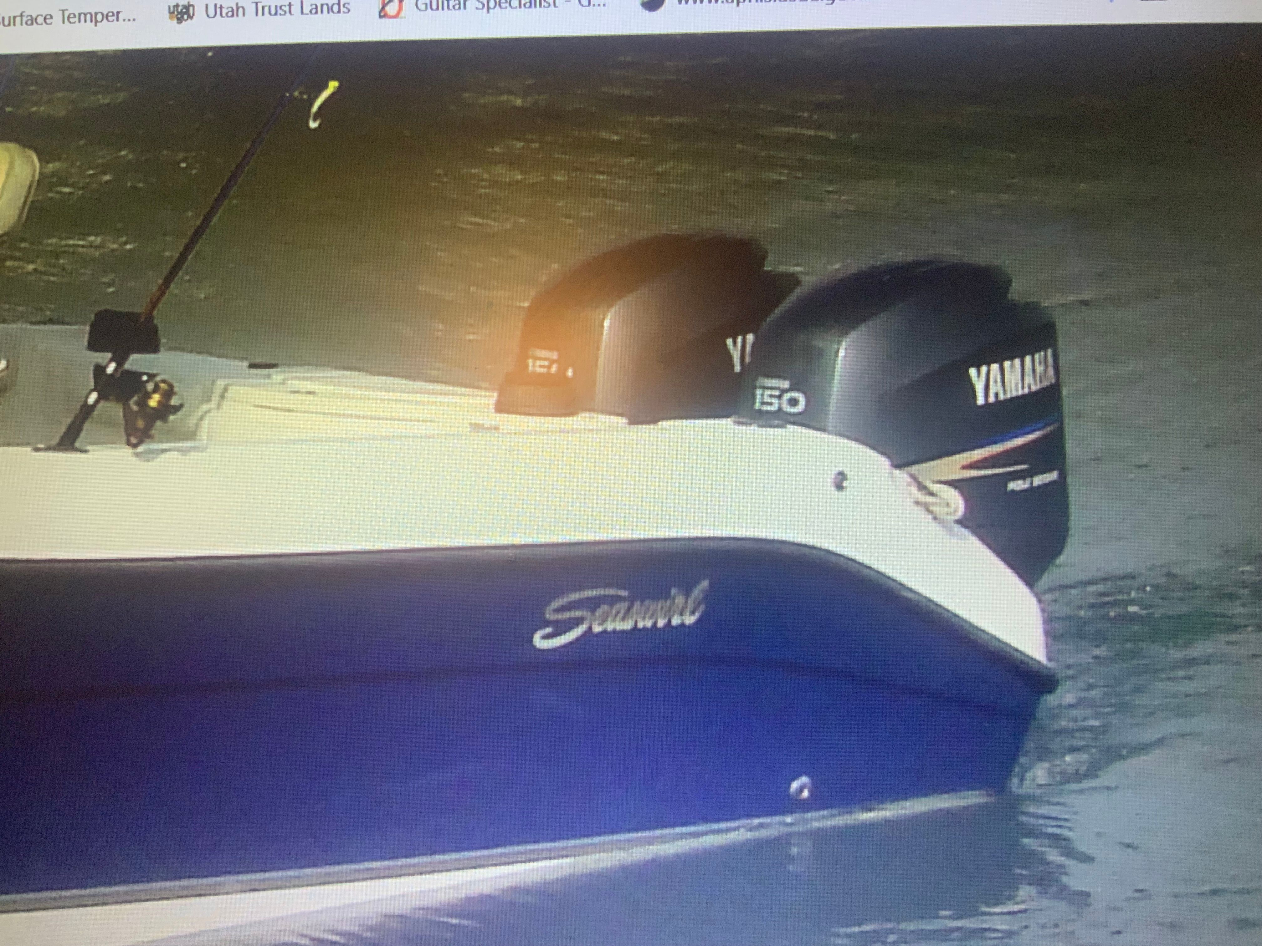 A blue and white 2006 Seaswirl Striper 26 with two Yamaha outboard motors on calm water.