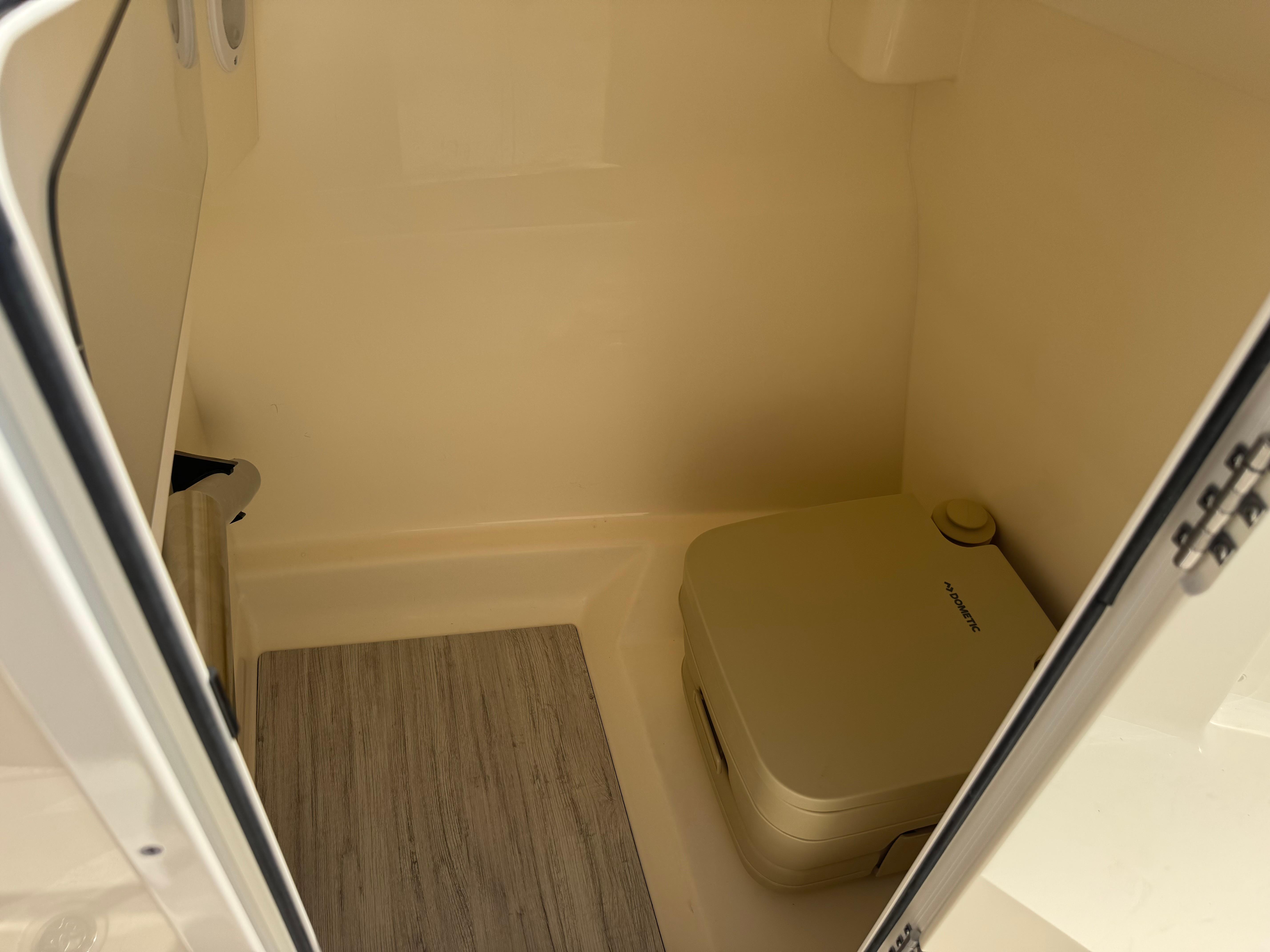 2025 Scout 215 Dorado boat interior with portable toilet and wooden flooring.