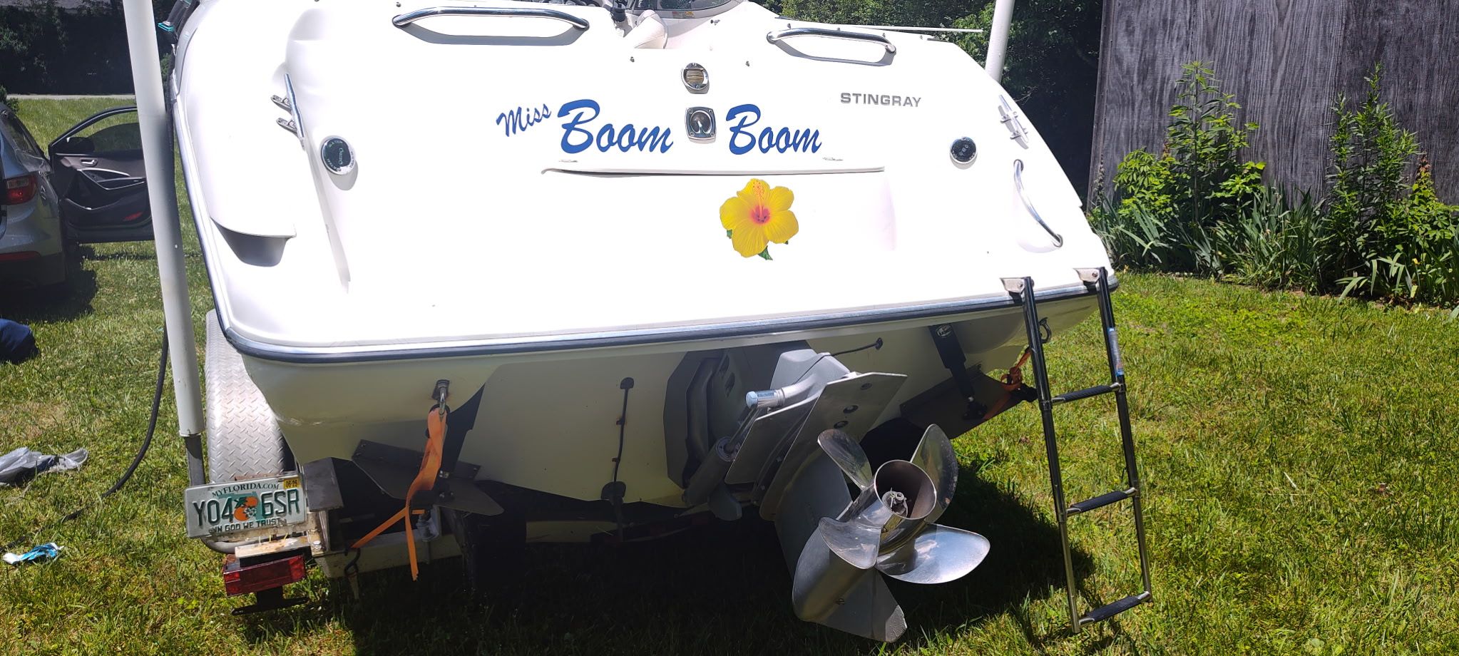 The image shows the stern of a white boat named "Miss Boom Boom" with a flower.