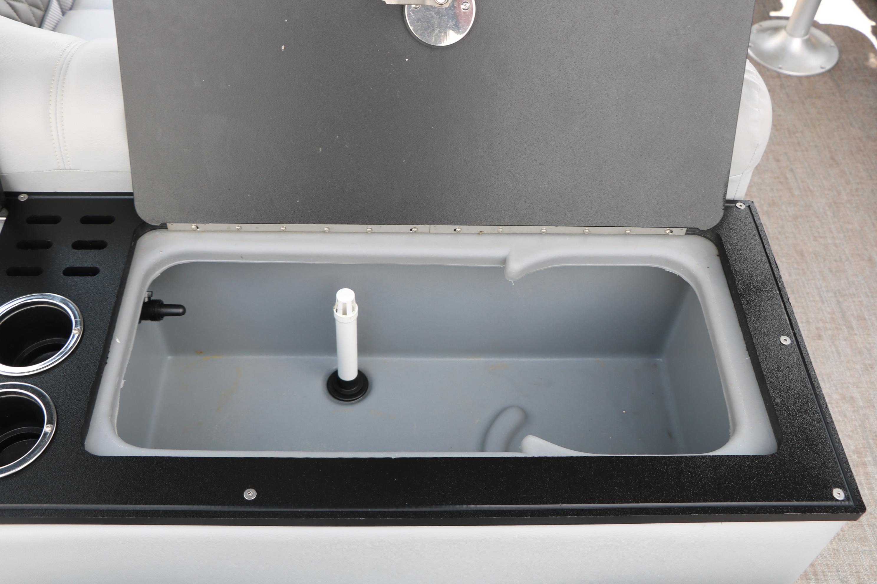 Open storage compartment on 2021 Ranger 223FC boat with cup holders and drainage system.