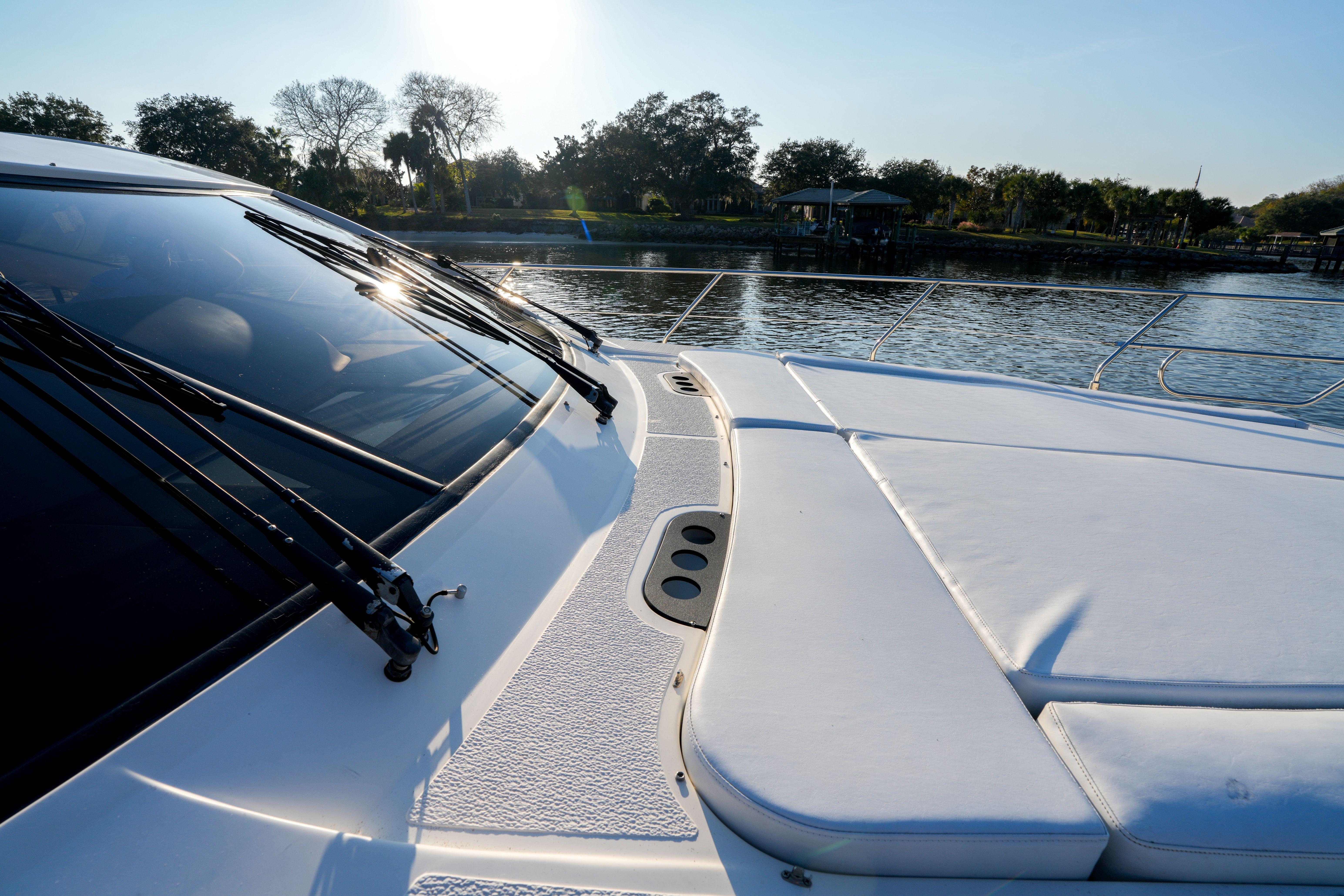 2007 Astondoa 53 Open Cruiser yacht deck with sunpad, docked by a scenic waterfront.