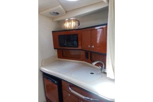2005 Sea Ray 300 Sundancer galley with microwave, sink, and storage cabinets.