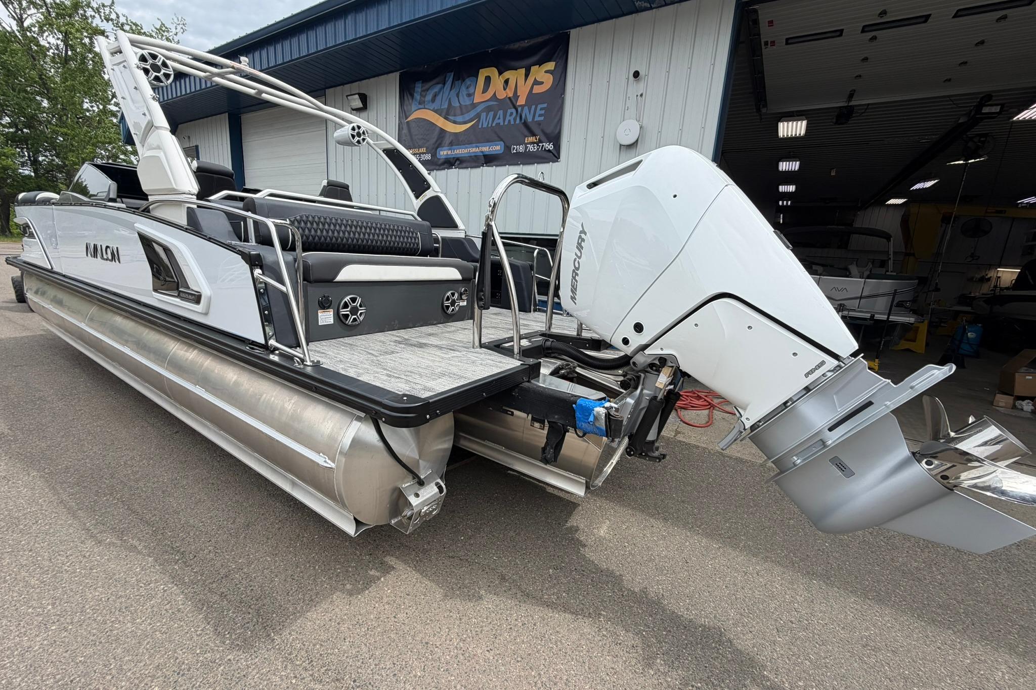 2026 Avalon Excalibur LTD Flex Lounge pontoon boat with Mercury outboard motor, docked outdoors.