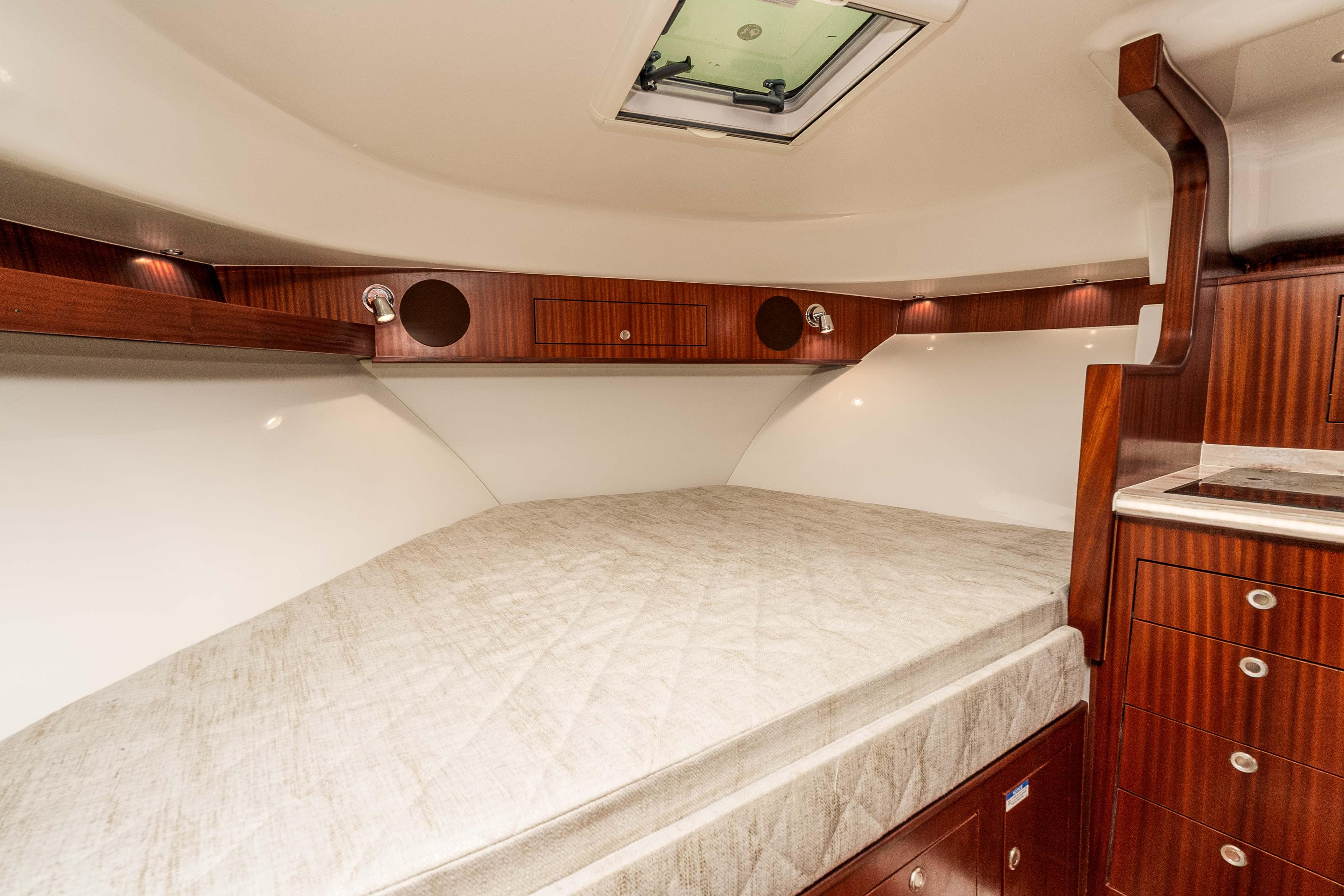 Luxurious cabin interior of 2022 Pursuit OS 385 Offshore boat with wood accents.